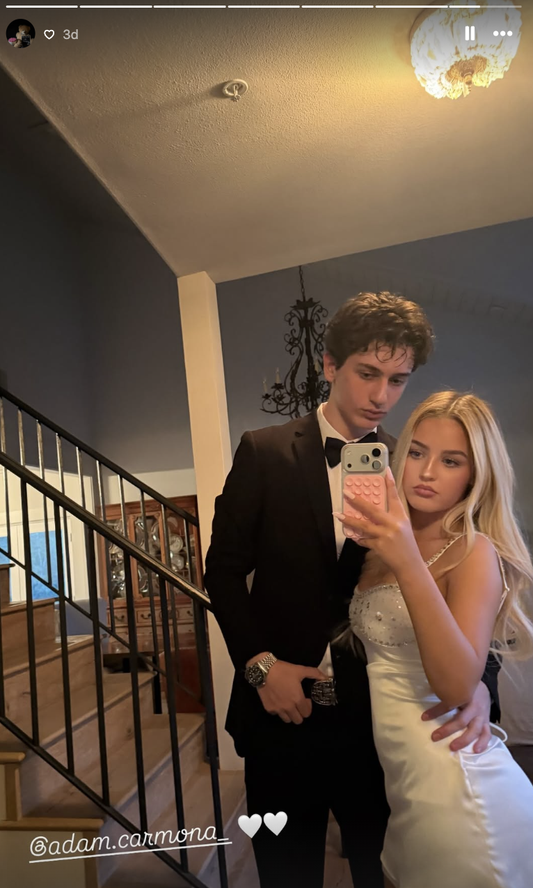 Finley Lockwood poses for a staircase mirror selfie alongside date Adam Carmona, wearing an embellished white satin strapless mini dress detailed with sparkling crystal accents along the neckline, while he wears a classic black tuxedo and bow tie. | Source: Instagram/finleyl.ockwood