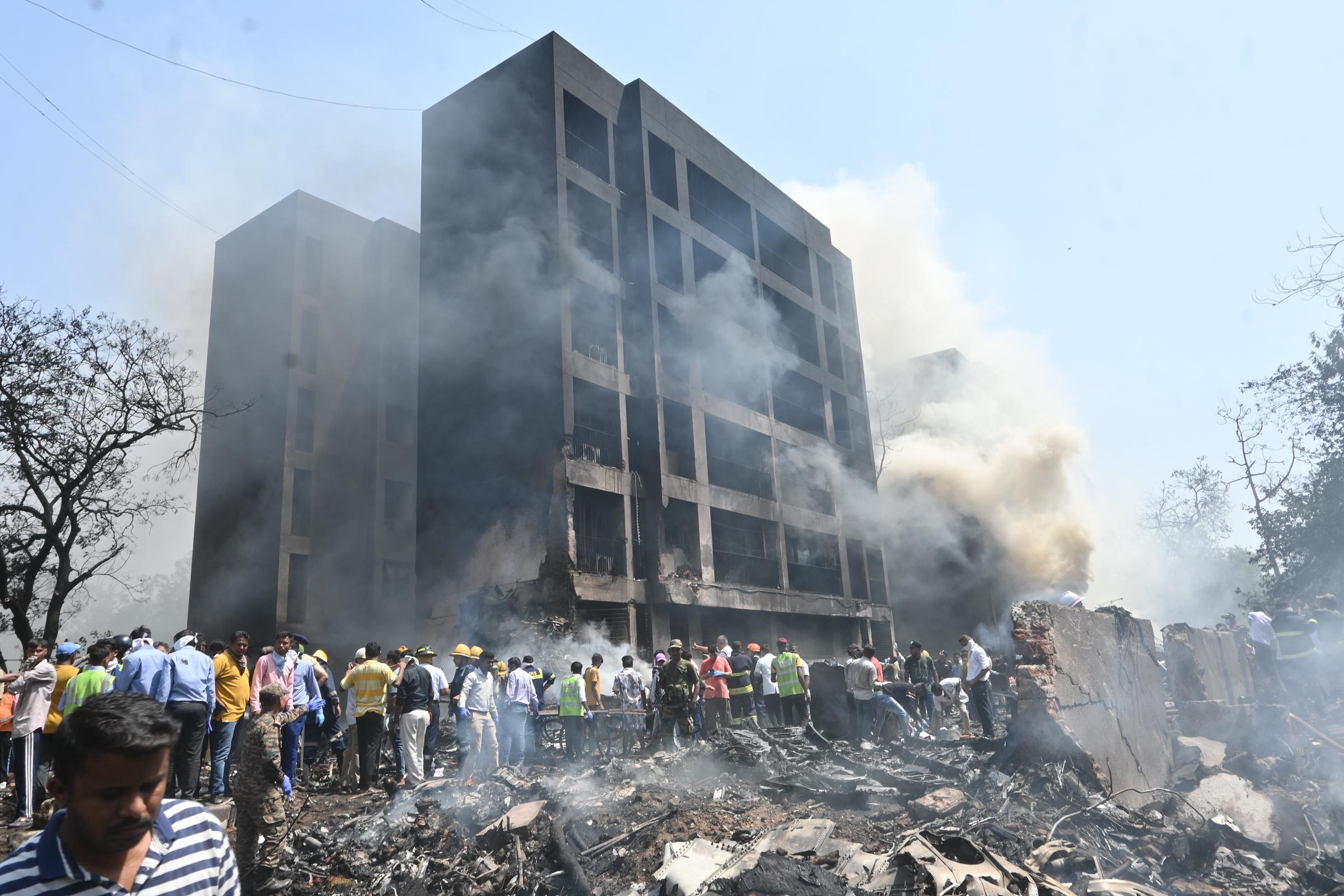 Smoke rises from a damaged building as people gather at the crash site in Ahmedabad, India, on June 12, 2025 | Source: Getty Images