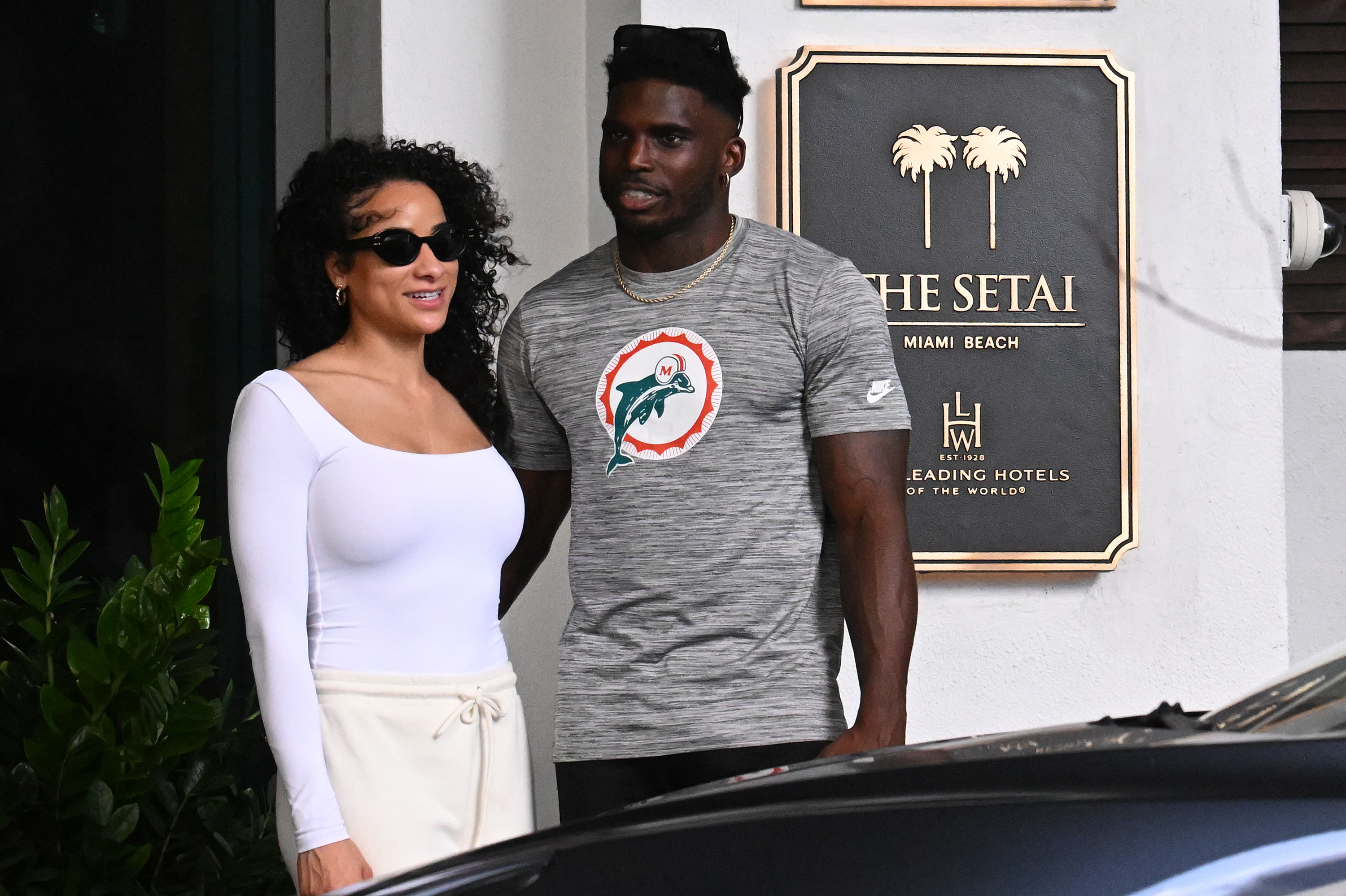 Tyreek Hill and his wife, Keeta Vaccaro, stand together outside The Setai in Miami Beach, Florida, with the Dolphins wide receiver wearing a gray team T-shirt while Vaccaro opts for an all-white ensemble and dark sunglasses. The couple were photographed during a seaside lunch outing on January 28, 2024, less than three months after they tied the knot on November 8, 2023.