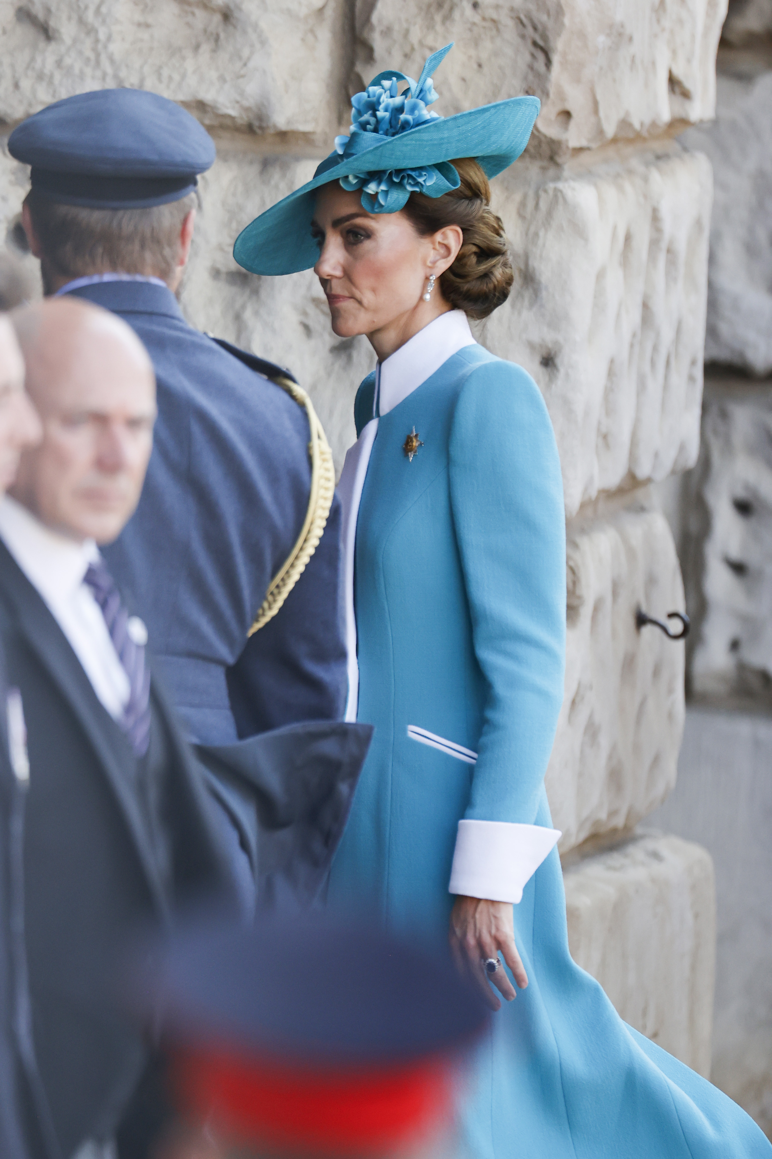 A full side-angle shot captures Princess Catherine’s 2025 Trooping the Colour ensemble in striking detail. Her tailored teal coat, accented with bold white cuffs and collar, is complemented by a matching floral-adorned hat. The angle highlights the refined lines of her outfit and the elegance of her posture as she engages with the ceremonial proceedings.
