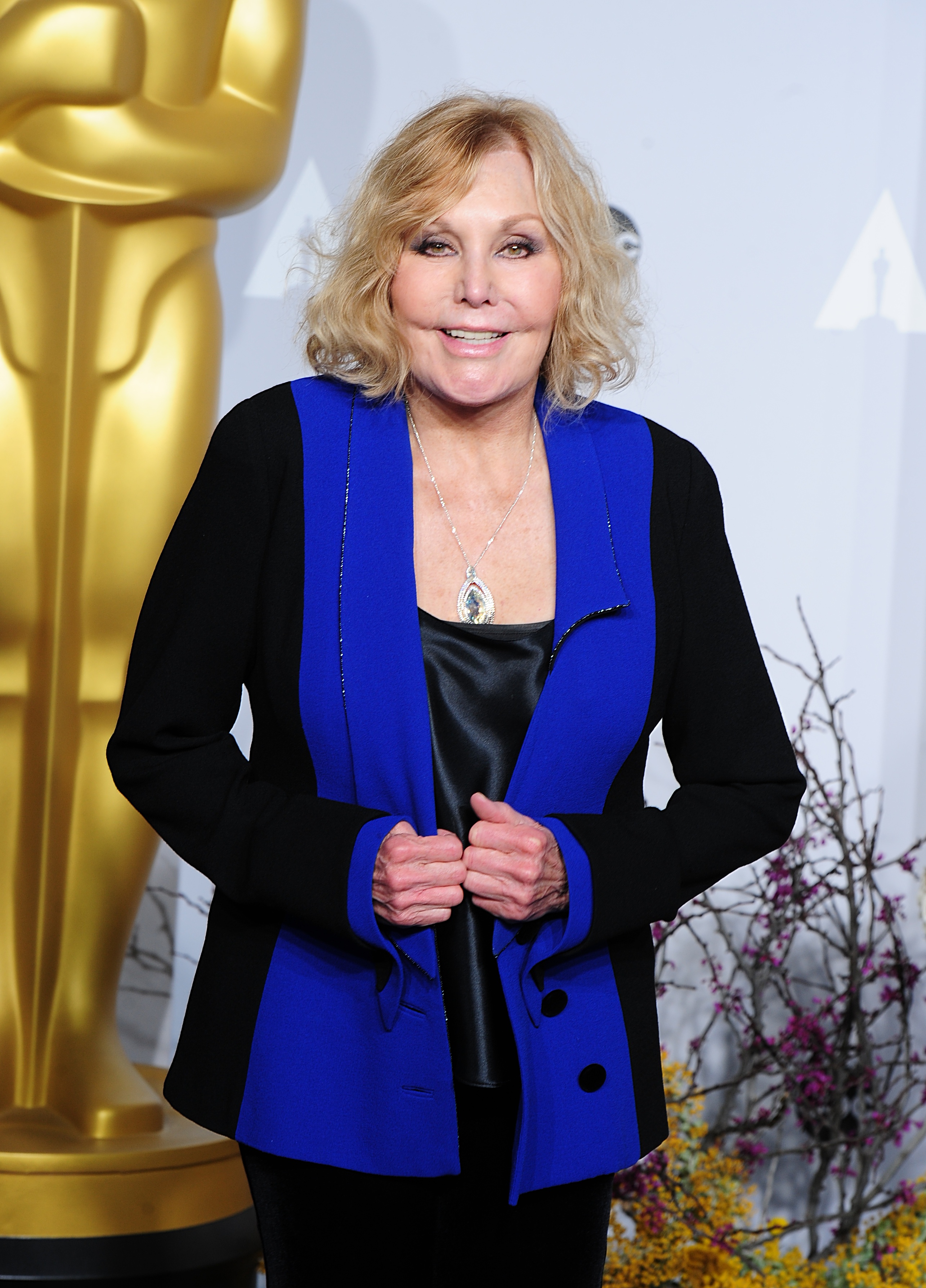 Kim Novak smiles for photographers in a black outfit with vivid blue lapels at the 86th Academy Awards in Hollywood on March 2, 2014. | Source: Getty Images