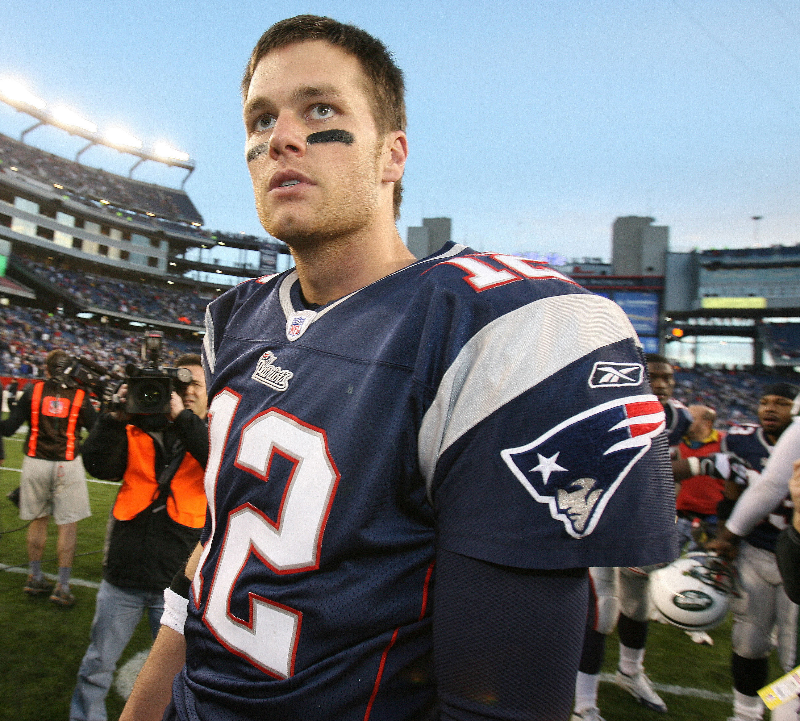 Under the bright lights of Gillette Stadium, Tom Brady commanded the field with signature poise during the Patriots' Wildcard victory over the Jets. He is dressed in his uniform and wearing a battle-ready expression on his face.