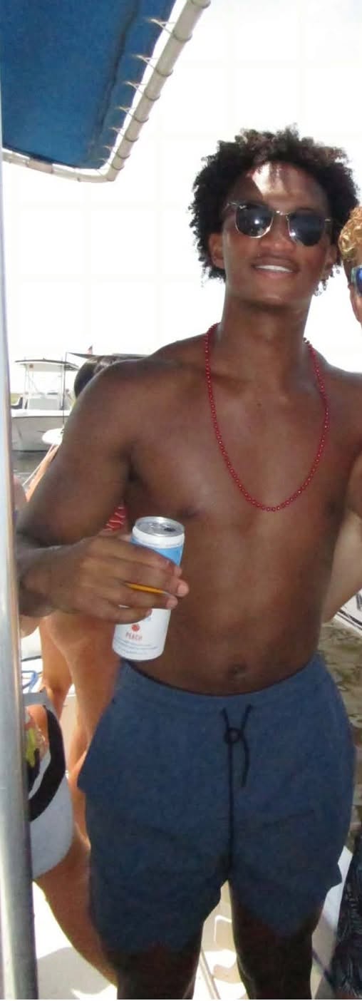 Nolan Wells smiles while holding a drink on the boat during the July 4 celebrations. He spent the afternoon wearing blue swim trunks, sunglasses, and a red beaded necklace. | Source: Facebook/christine.wonsley