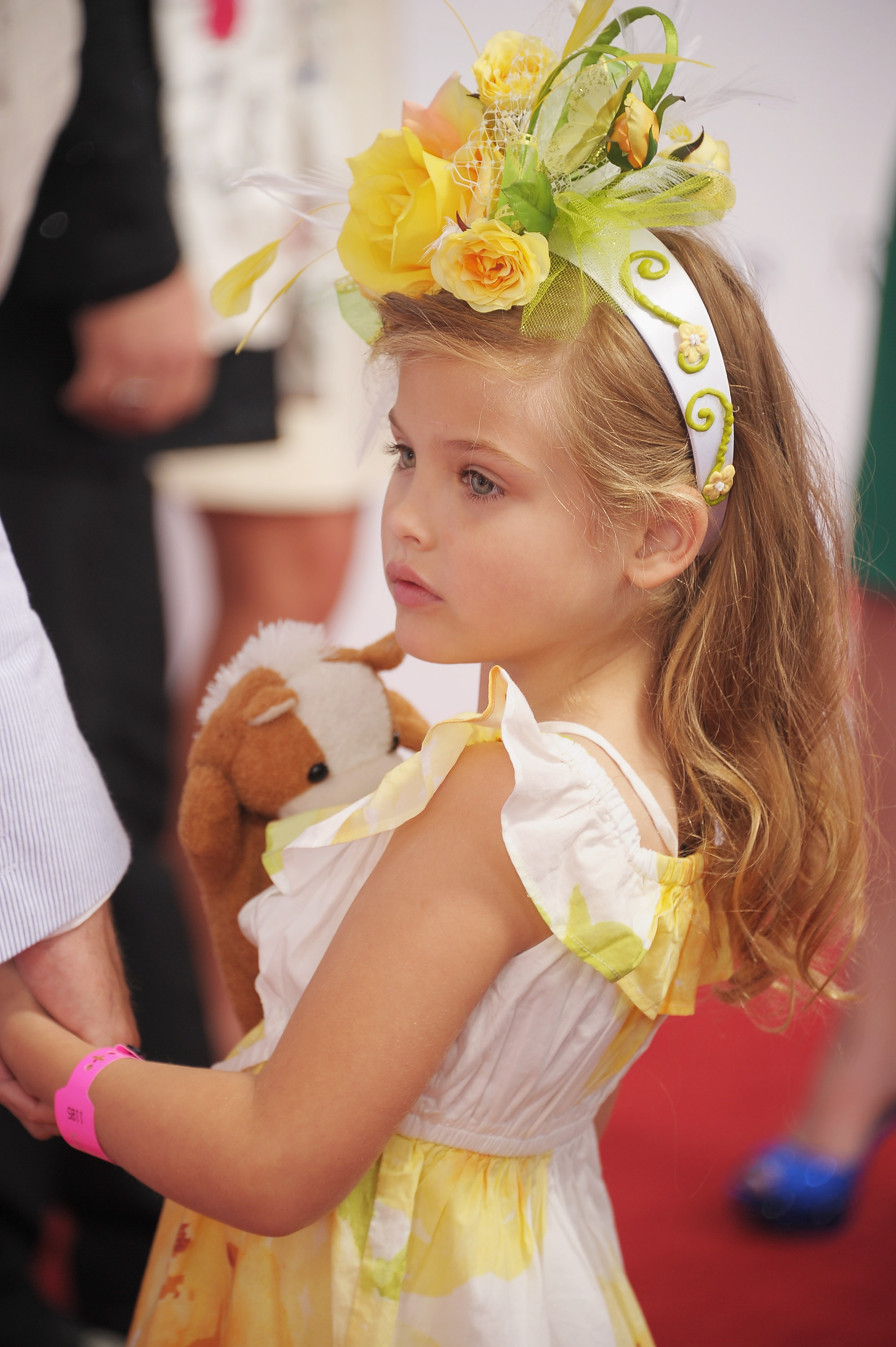 Clutching a plush stuffed pony and gazing thoughtfully off to the side, 5-year-old Dannielynn Birkhead captured classic southern charm at the 138th Kentucky Derby on May 5, 2012. An elaborate floral fascinator blooming with yellow roses and greenery rested atop her cascading blonde waves, perfectly complementing her sunny, tiered sundress as she gracefully stepped into another year of her public journey.