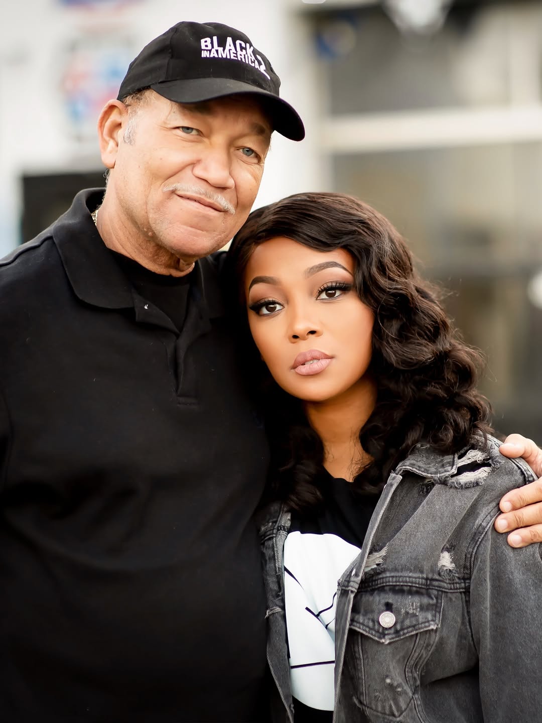 Monica looks straight at the camera while her father wraps an arm around her. | Source: Instagram/monicadenise