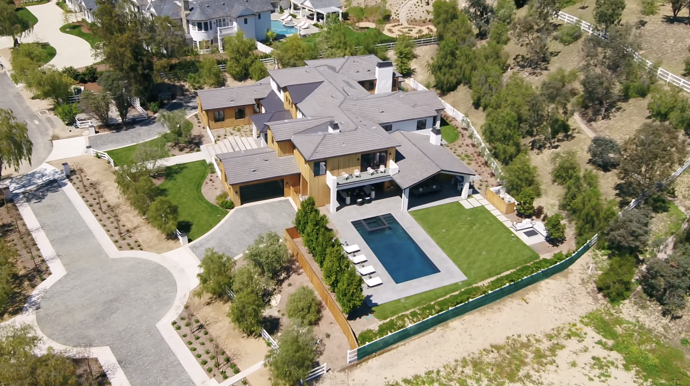 From the opposite side, the home's outdoor layout comes into clearer focus. A rectangular pool, broad lawn and several covered areas occupy the private space behind the residence. | Source: Youtube/Tomer.Fridman