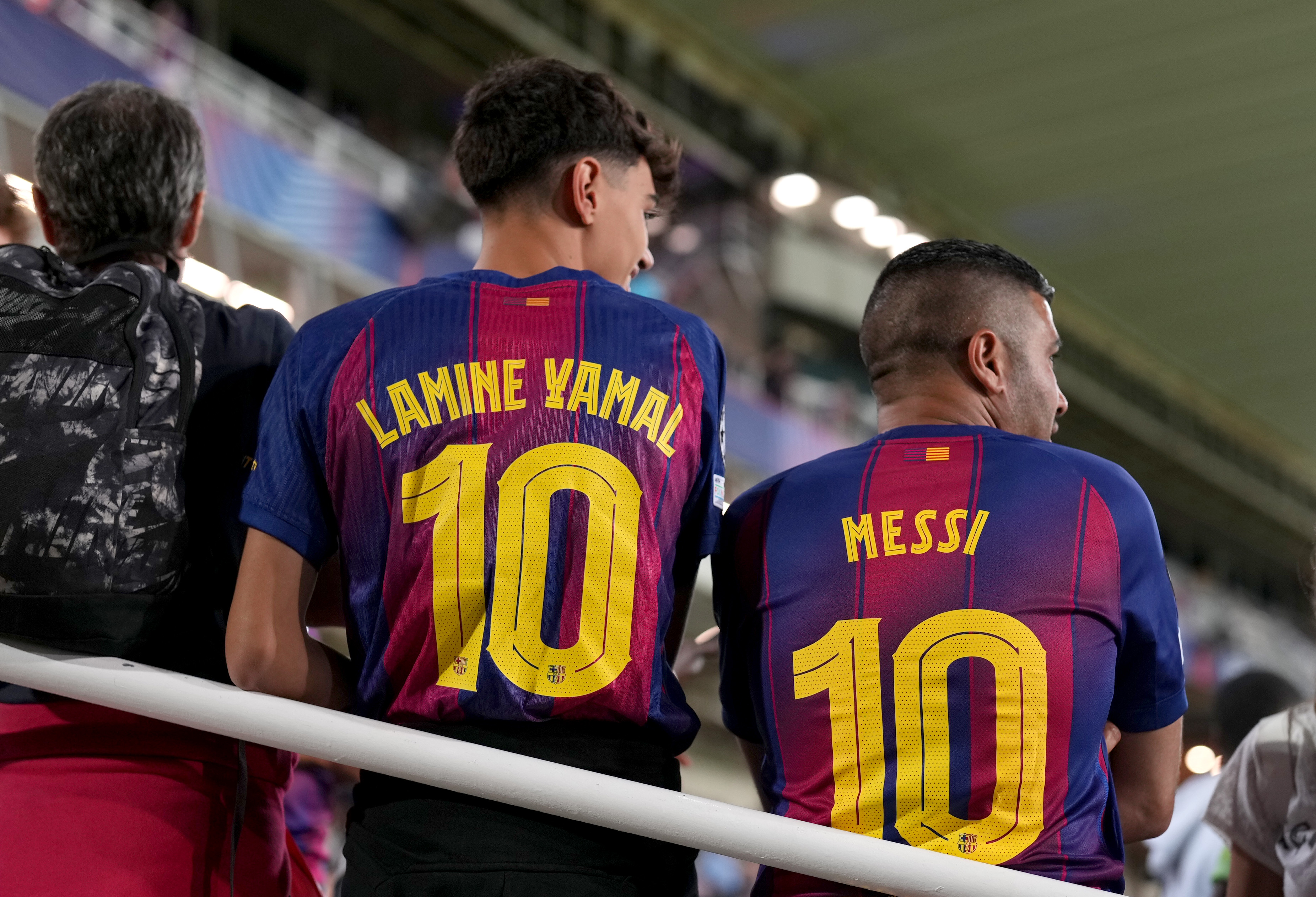 Fans of FC Barcelona pose for a photo while displaying the names of Lamine Yamal and Lionel Messi on October 1, 2025, in Barcelona, Spain. | Source: Getty Images