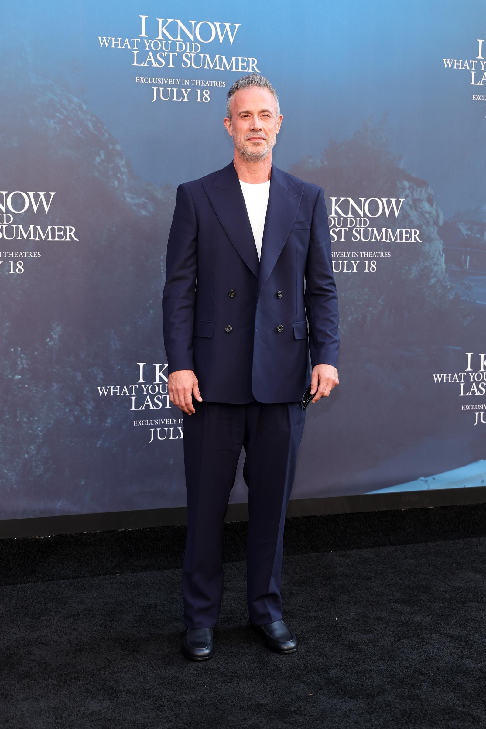 Prinze Jr. in a solo shot in a navy double-breasted suit worn over a white crew-neck tee. He paired the look with black shoes and a relaxed stance.