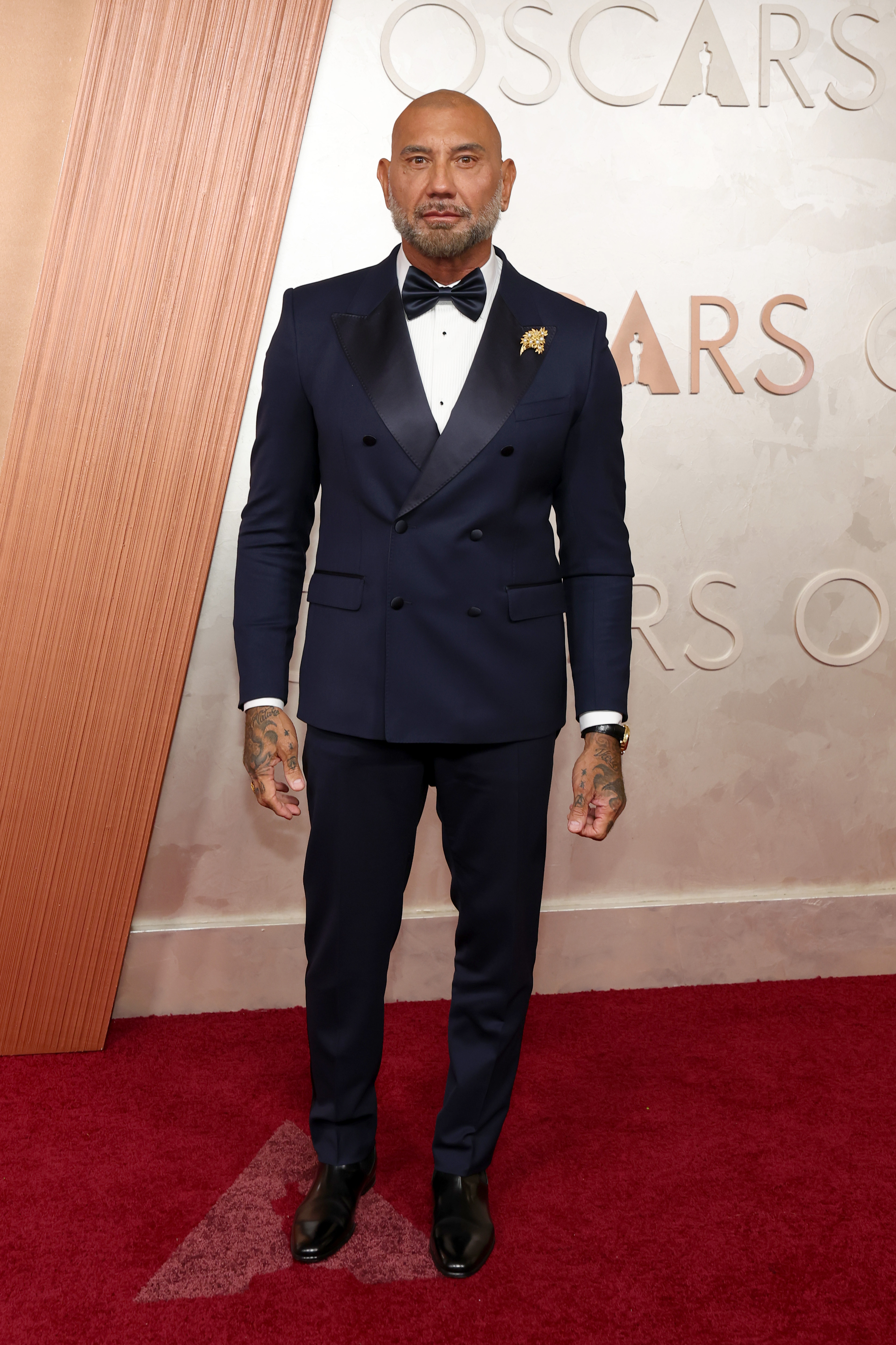Dave Bautista put his noticeably leaner physique on display as he arrived at the 97th Annual Academy Awards at the Dolby Theatre in Hollywood, California, on March 2, 2025. Wearing a sharply tailored navy tuxedo with a black bow tie, the former WWE star appeared significantly slimmer than the heavily muscled figure audiences had grown accustomed to seeing. The red carpet appearance came after Bautista had revealed that he had lost 75 pounds and explained that trimming down left him feeling better while also helping him look better on camera alongside other actors.