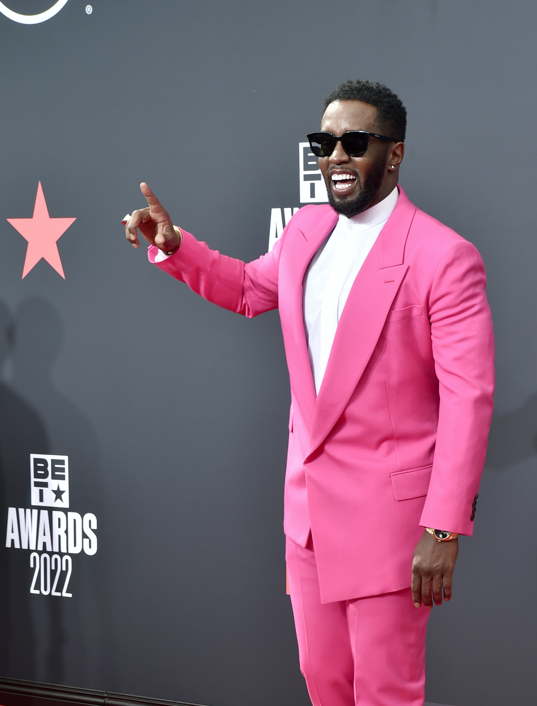 Sean "Diddy" Combs flashes a wide smile and points while arriving in a bold hot pink suit at the BET Awards in Los Angeles, California, on June 26, 2022.