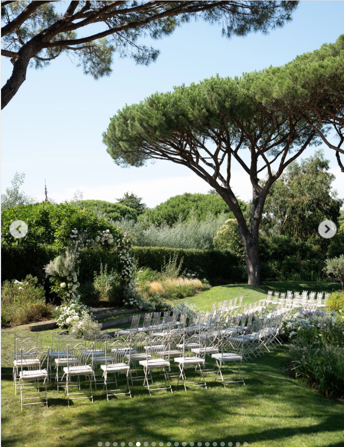 The ceremony unfolded in a lush Saint-Tropez garden, where rows of delicate chairs faced a flower-covered arch beneath towering umbrella pines and clear blue skies. | Source: Instagram/thierryjoubertphotography