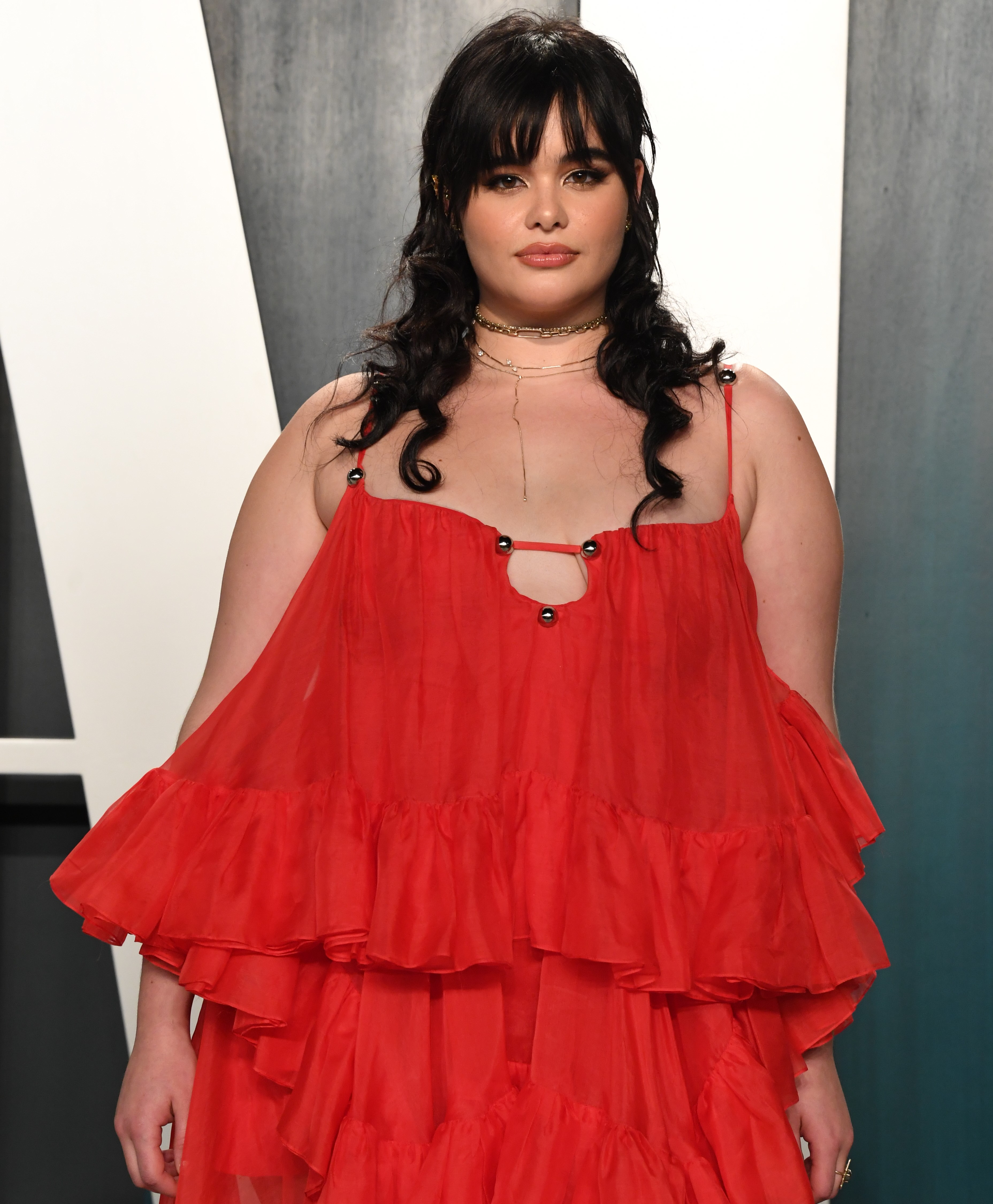 Ferreira is seen attending the 2020 Vanity Fair Oscar Party hosted by Radhika Jones at the Wallis Annenberg Center for the Performing Arts in Beverly Hills, California. She wears a flowing red tiered gown with delicate straps and layered ruffles. Her hair is styled in soft waves with curtain bangs, complemented by subtle glam makeup and layered gold necklaces.