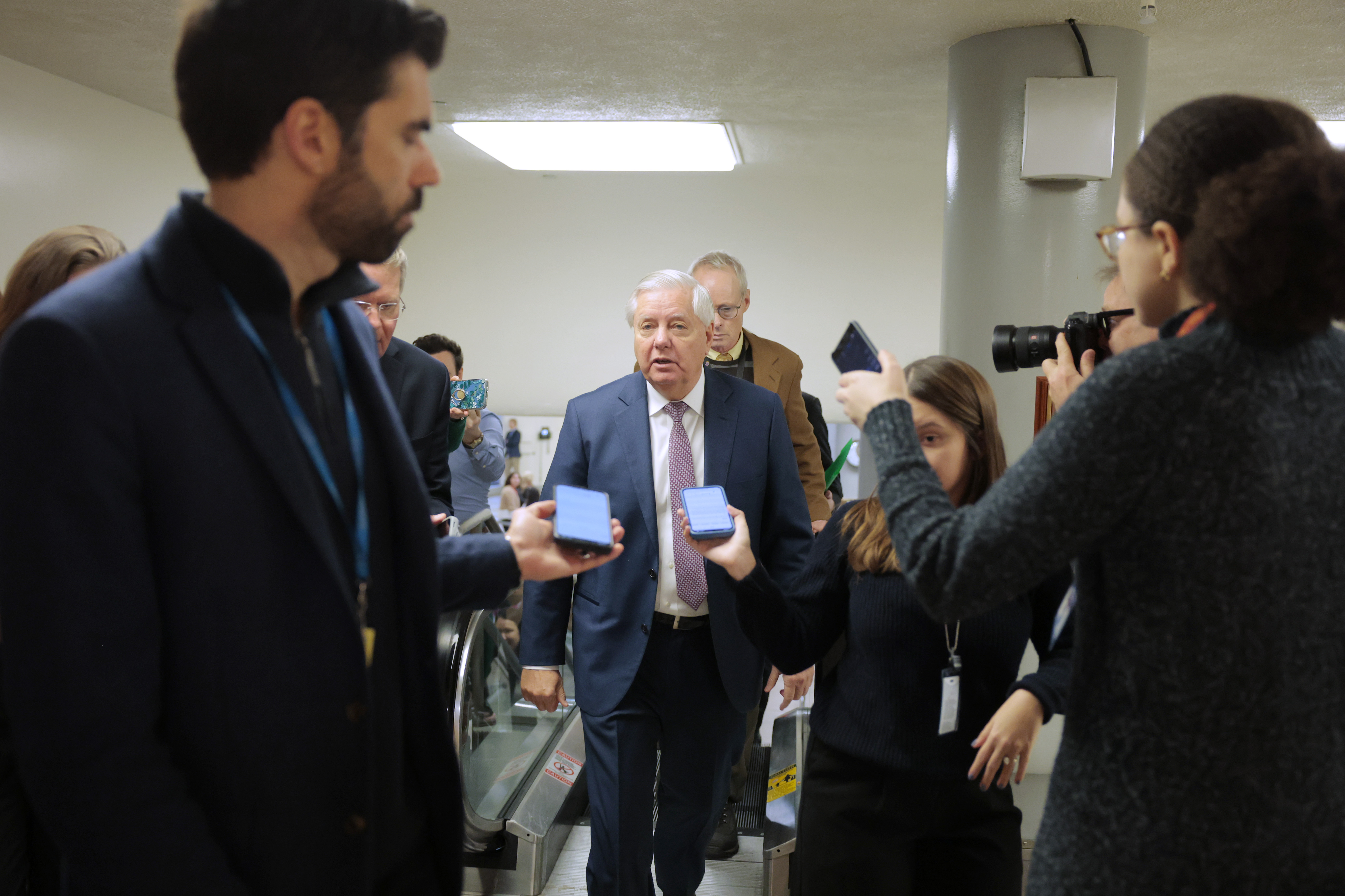 Lindsey Graham pauses in the Capitol's Senate subway to answer questions from journalists while moving between confirmation votes, underscoring his role in a fast-moving legislative day. | Source: Getty Images