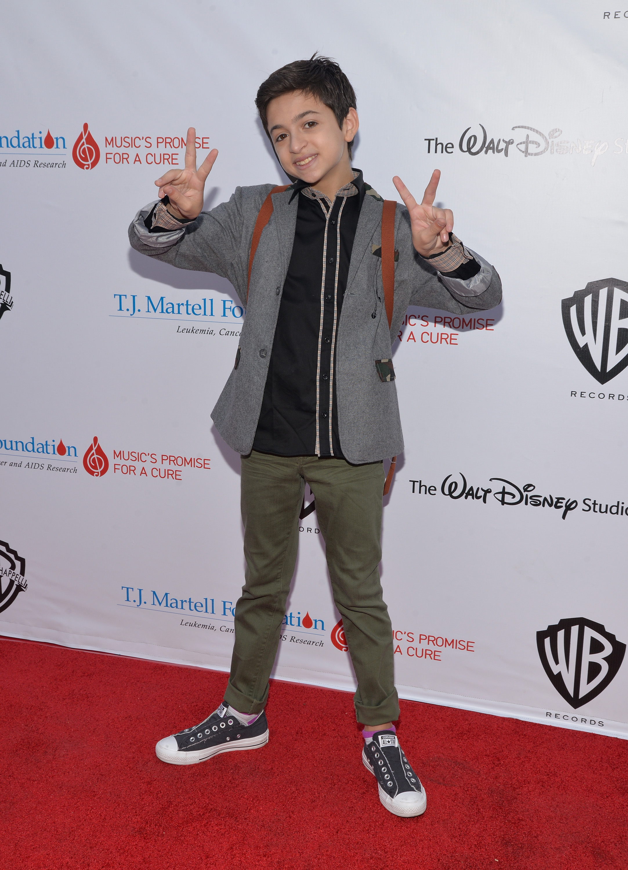 She flashes peace signs on the red carpet at the T.J. Martell Foundation's 6th Annual Family Day LA event in Studio City, California, wearing a gray blazer, a black shirt, olive-green trousers, and black high-top sneakers. | Source: Getty Images