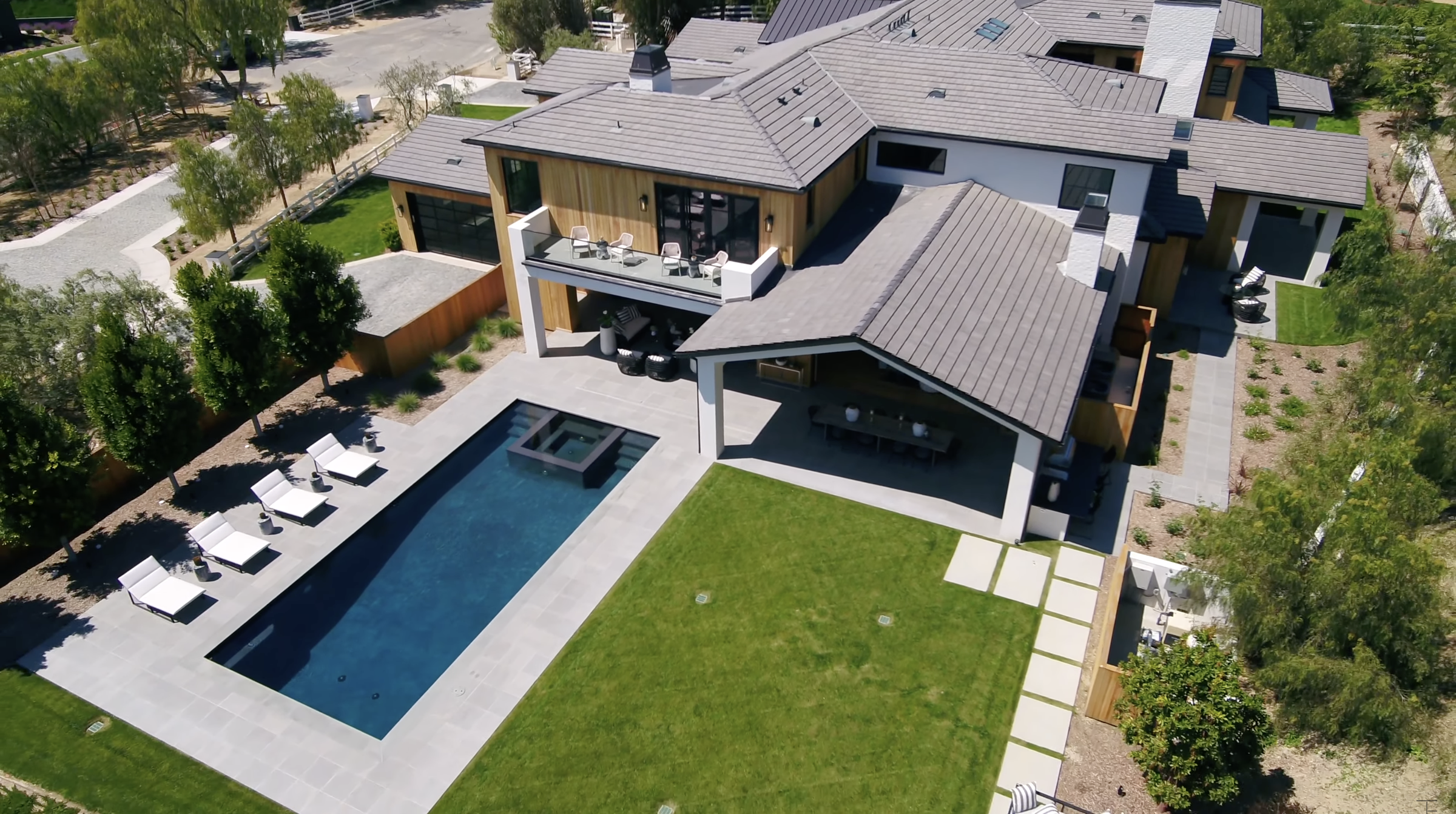 A long rectangular pool occupies one side of the backyard, leaving a broad stretch of lawn alongside it. Lounge chairs line the water, while the home's covered entertaining spaces face the pool. | Source: Youtube/Tomer.Fridman
