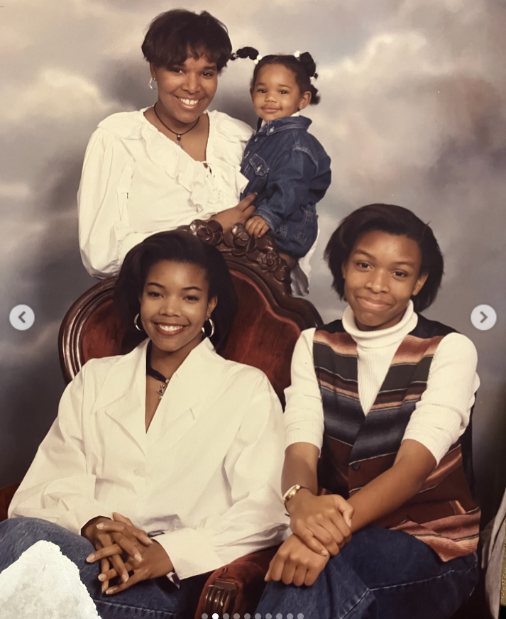 Gabrielle Union sits alongside a young girl in a formal family portrait, while an older woman stands behind them holding a toddler; all face the camera against a soft, clouded backdrop. | Source: Instagram/gabunion