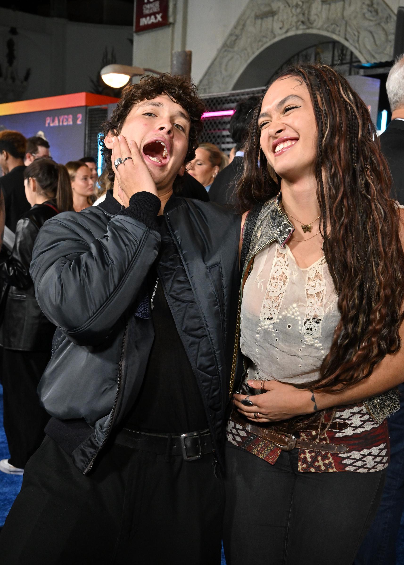 Siblings Nakoa-Wolf Momoa and Lola Iolani Momoa share an animated, playful laugh together on the blue carpet at the Los Angeles premiere of Paramount Pictures' "Street Fighter" at the TCL Chinese Theatre on October 12, 2026, in Hollywood, California. Nakoa-Wolf makes an exaggerated shocked expression with his hand resting on his cheek while wearing his dark bomber jacket and belted trousers, as Lola laughs alongside him with her long braided waves falling over her shoulders. | Source: Getty Images