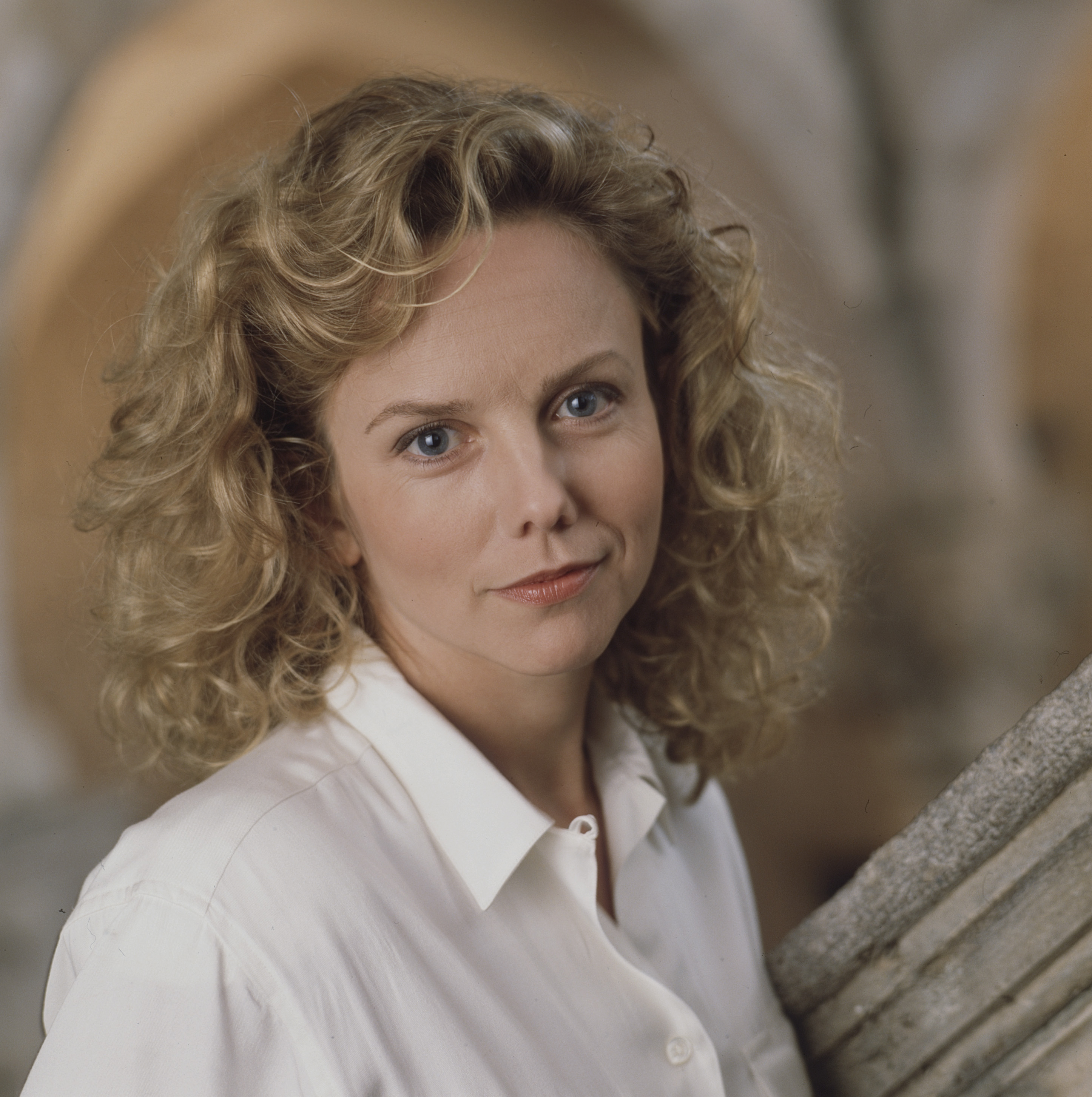 Gone was the soft, cherubic roundness of her early 20s; by 1989, Linda Purl’s facial structure had matured into distinct, statuesque angles with defined cheekbones and a subtle, knowing smirk. Photographed in Los Angeles for the TV movie "Under Cover", the 34-year-old actress paired a crisp white collared shirt with a head of voluminous, shoulder-length blonde curls that signaled her shift into confident adult leading roles.