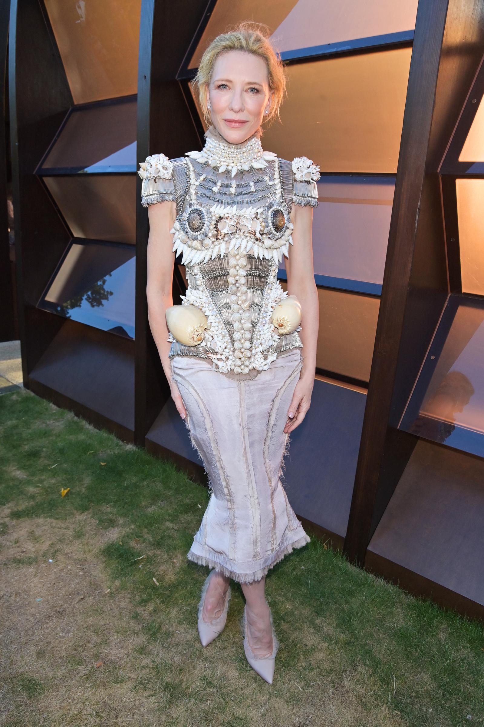 She wore pointed nude pumps with a satin finish, keeping the footwear neutral against the detailed textures of the dress.
