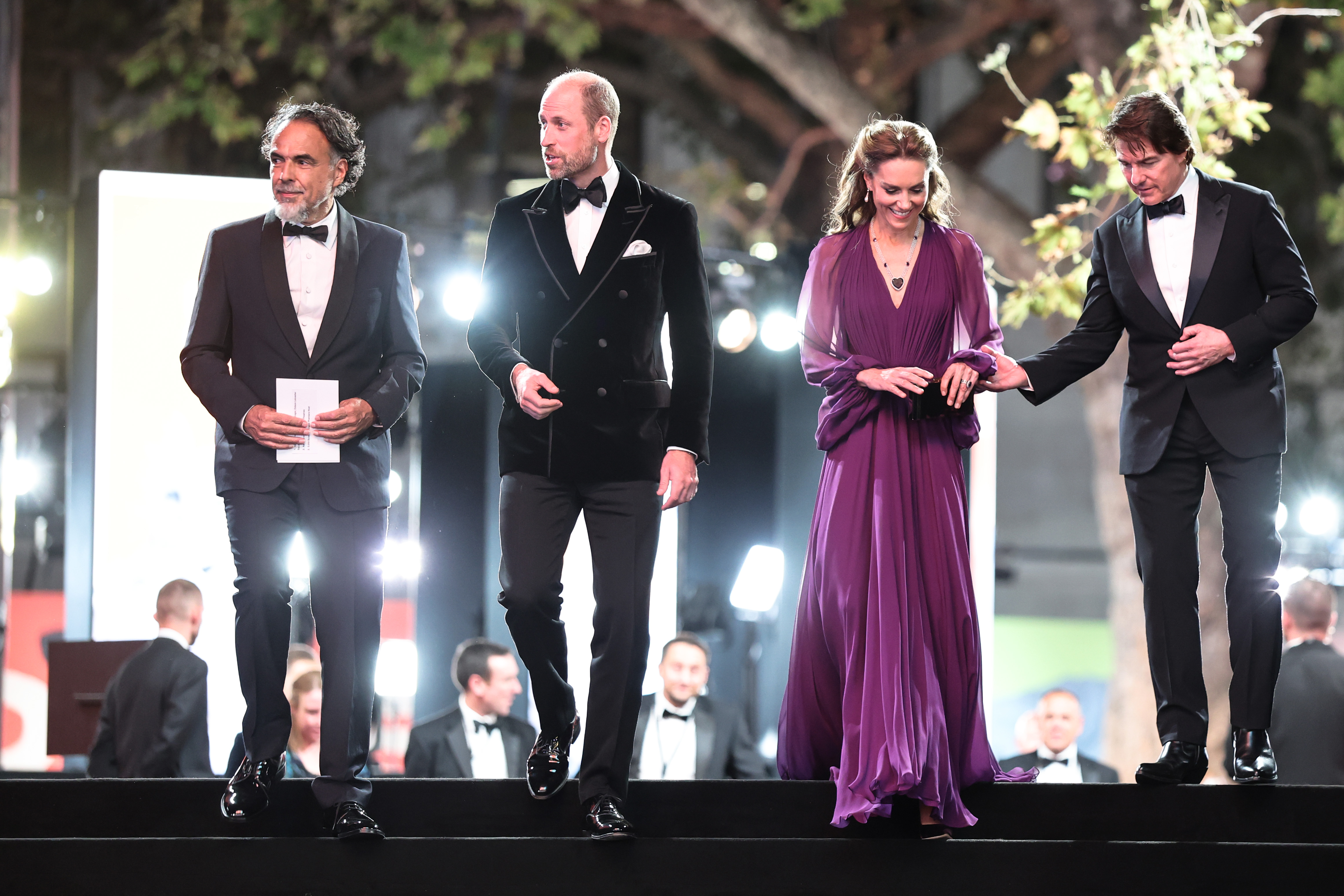 Alejandro, William, Catherine, and Tom are pictured together on the steps at the "Digger" World Premiere and Royal Film Performance. Tom extends a hand toward Catherine as the group moves along the staircase.