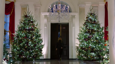 U.S. First Lady Melania Trump walking between two towering Christmas trees in the White House, posted on December 1, 2025. | Source: Facebook/First Lady Melania Trump