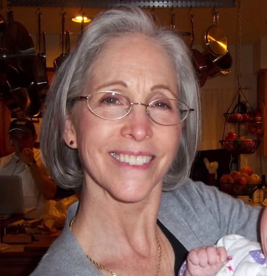 Caption: Rebecca Schmidt smiles in a personal family photograph, with a baby's tiny hand visible beside her — a tender glimpse of her life beyond her decades-long veterinary career. | Source: Rebecca Schmidt / Facebook.