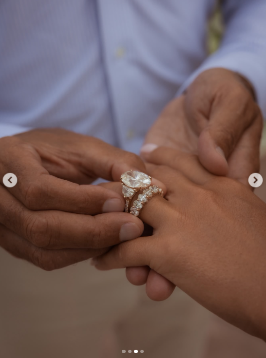Galanis slips the diamond ring onto Chrisley's finger, offering a close-up of its prominent oval-shaped center stone and sparkling setting. | Source: Instagram/ngdiamondgirl