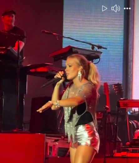Carrie Underwood leans forward with one hand stretched and microphone in the other, as seen from a video post dated November 30, 2025.| Source: Facebook/thecountrywire