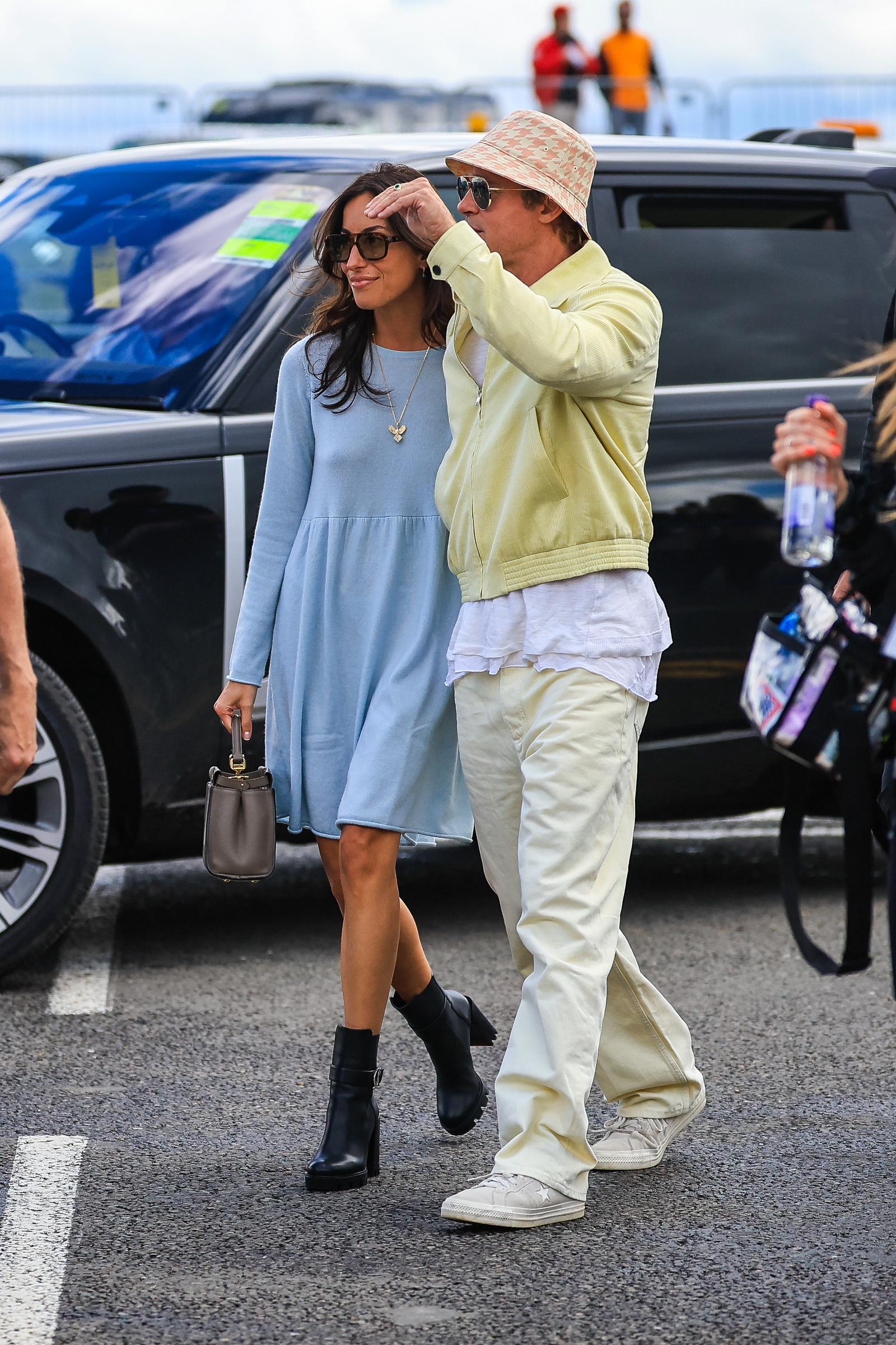 Pitt and de Ramon arrived in the paddock during the British Grand Prix at Silverstone Circuit in England, their first public event together. De Ramon wore a light blue dress with black boots, while Pitt paired pale separates with a patterned bucket hat and sunglasses.