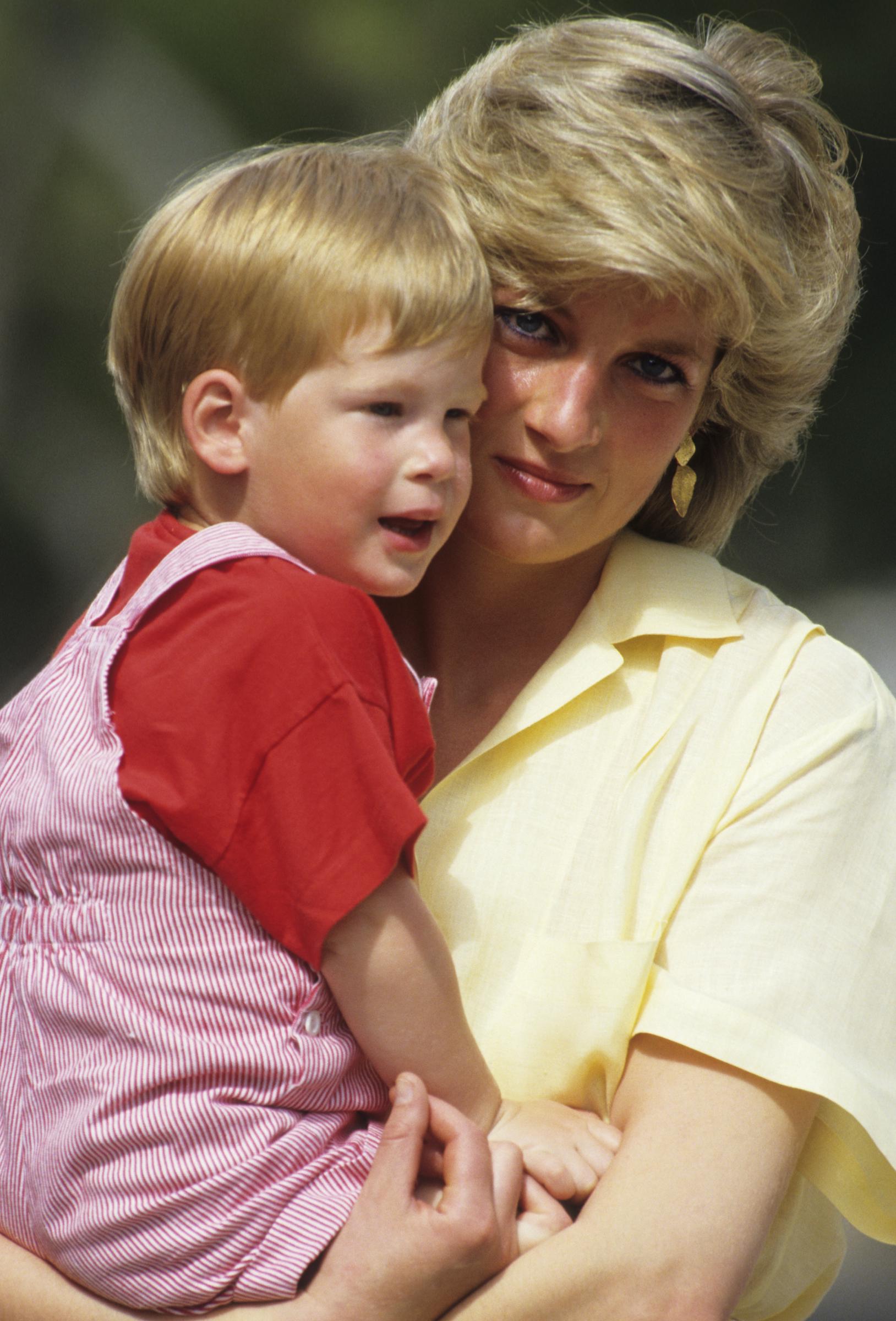 Princess Diana holds a young Prince Harry during a family holiday in Majorca, Spain, in August 1987. Decades later, a source said Diana's legacy remains an influence on Harry as tensions with the Royal Family continue. | Source: Getty Images