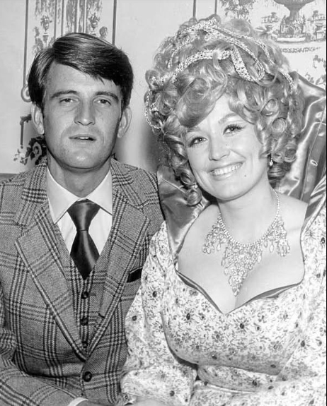 Parton and Dean sat closely together for this rare black-and-white portrait, with the country singer smiling brightly beside her husband. Both dressed formally for the photograph, Parton wore an embellished dress and jewelry, while Dean appeared in a patterned suit and tie. Despite Parton's increasingly public career, photographs of the couple remained relatively uncommon as Dean continued to keep his life and their marriage largely out of view. | Source: Facebook/One Country