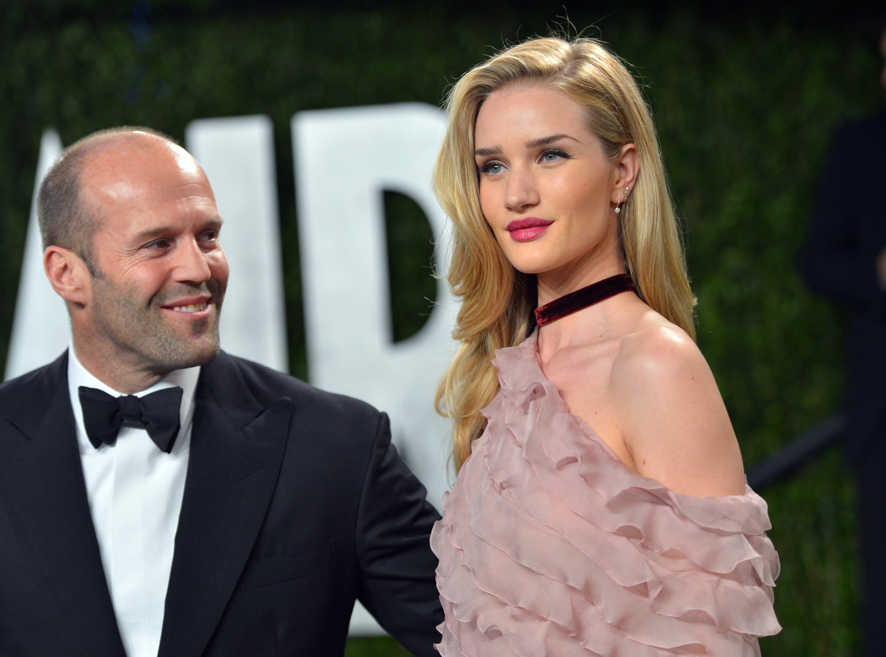 Rosie Huntington-Whiteley and Jason Statham share a red-carpet moment—classic black tie meets soft, romantic glamor, with just a hint of old-Hollywood allure. | Source: Getty Images