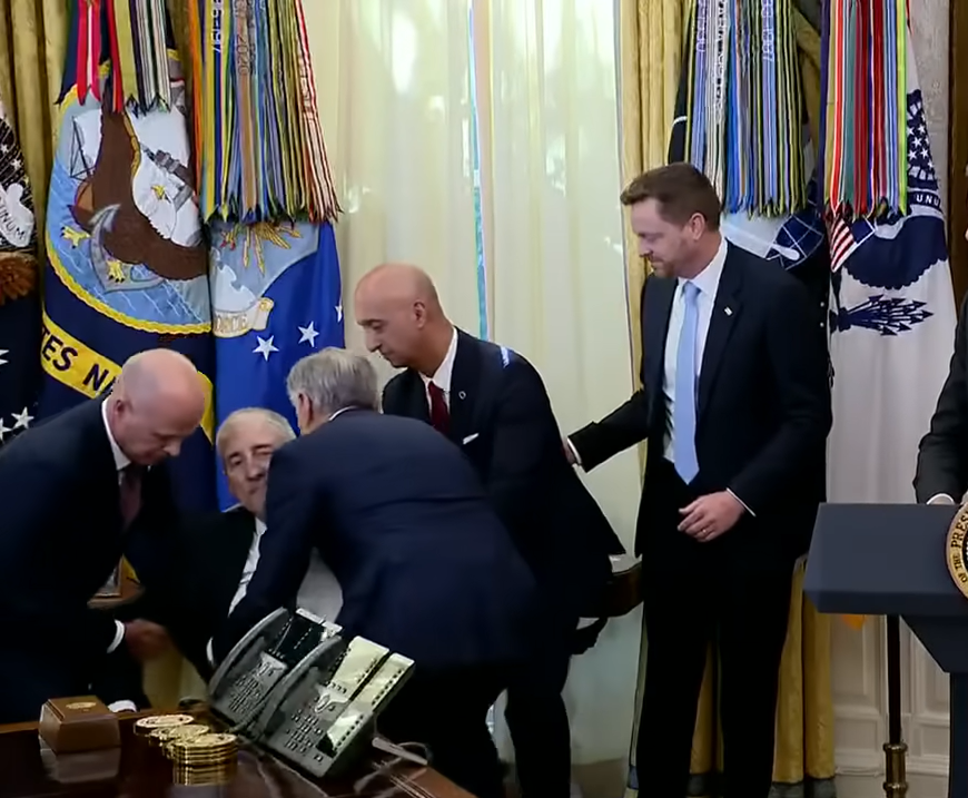 Gordon Findlay is supported by colleagues as he begins to collapse during the Oval Office event on November 6, 2025 | Source: YouTube/@fox5dc