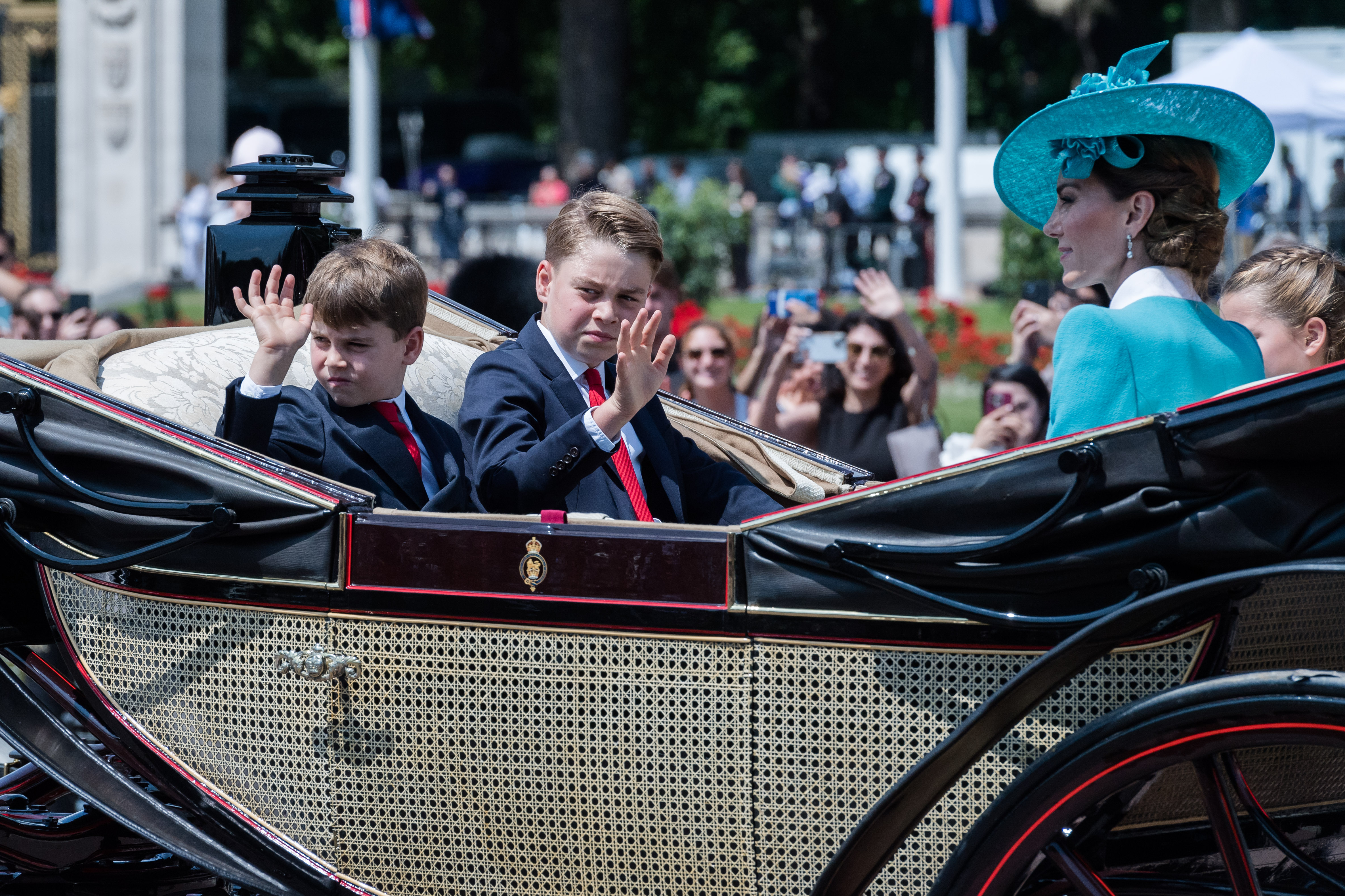 Prince Louis and Prince George waving to the crowd as Princess Catherine smiles with Princess Charlotte sitting next to her. | Source: Getty Images