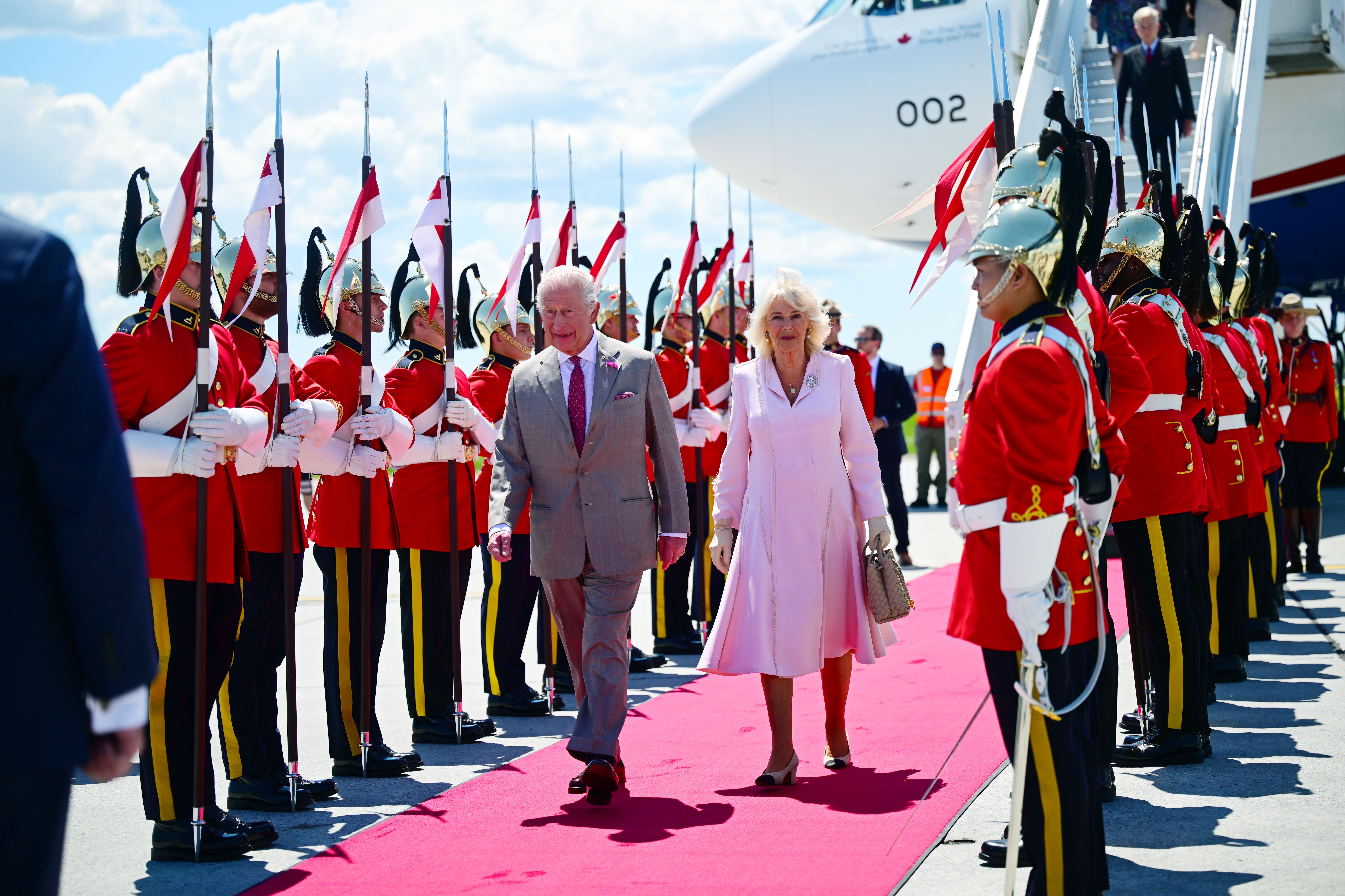 King Charles III and Queen Camilla walk majestically on a red carpet flanked by members of the Royal Canadian Mounted Police and the Canadian Armed Forces. It marks the King's 20th and the Queen's 5th tour of Canada.