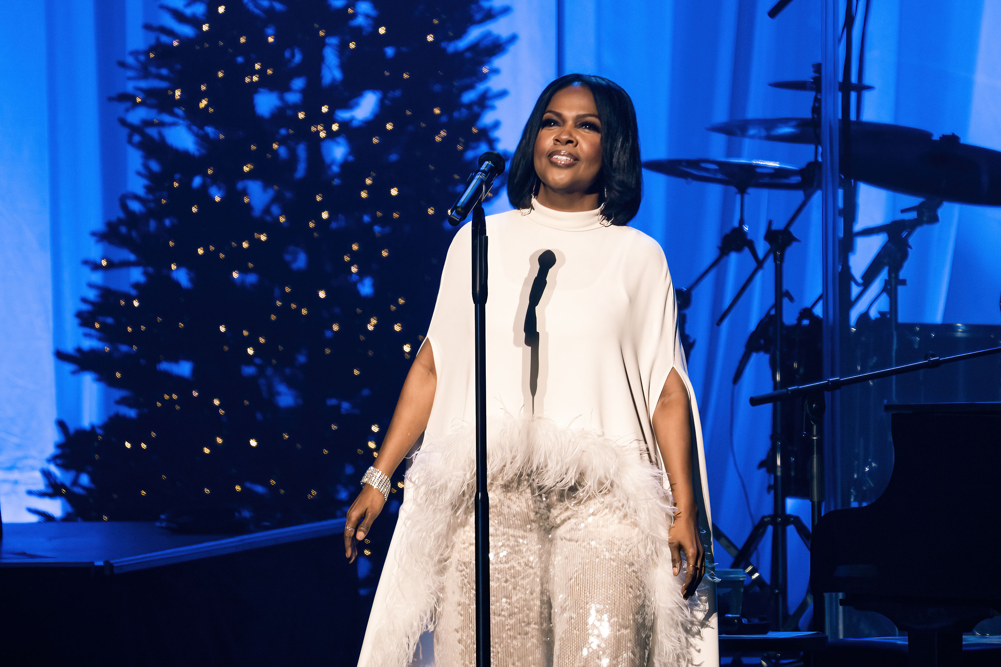 CeCe Winans walks across the stage in a flowing white outfit during Christmas With CeCe Winans Featuring Angie Winans & Debbie Winans in Sugar Land, Texas, on December 12, 2025.