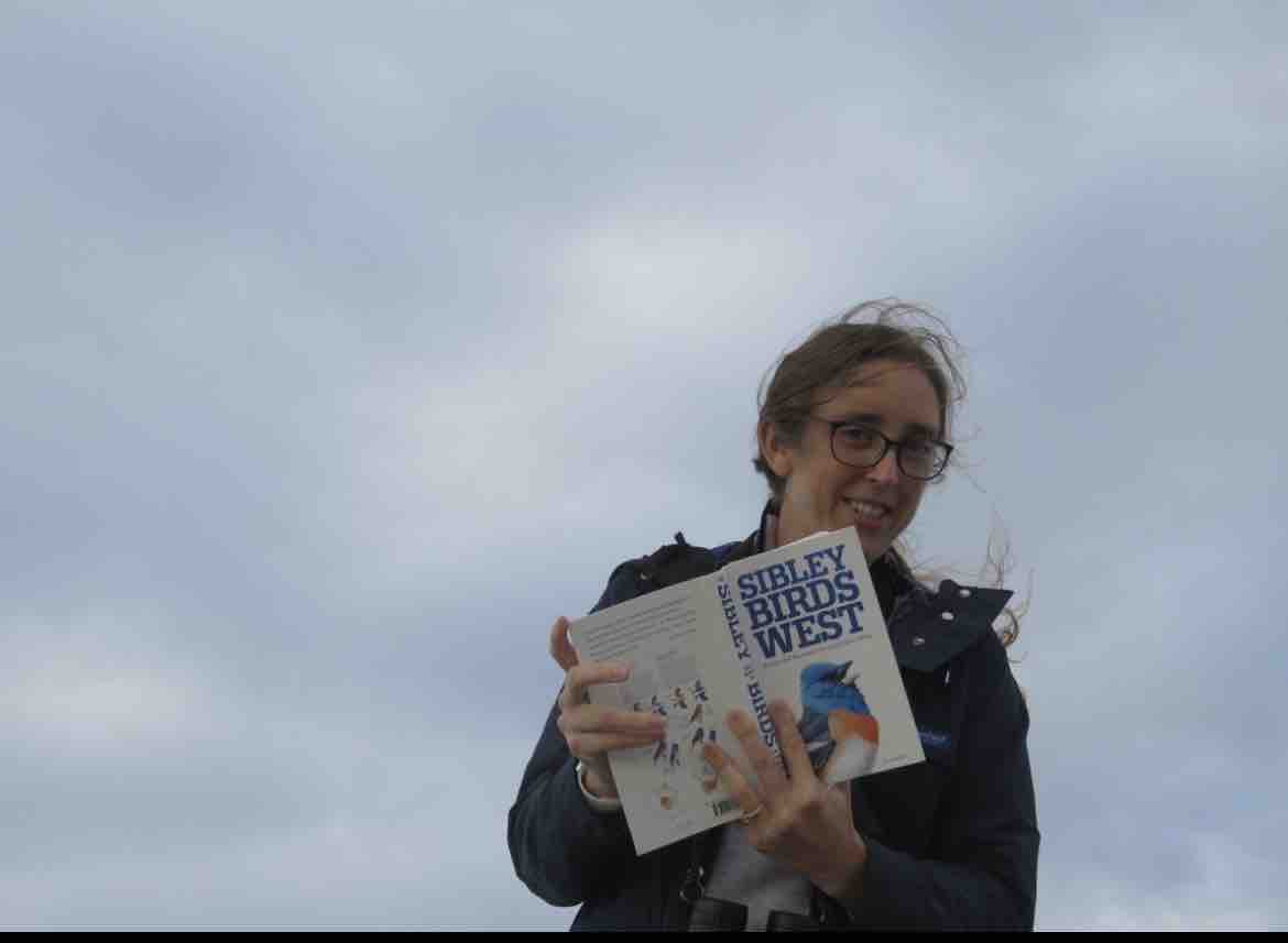 Dr. Julia Pederson smiles beneath an open sky while holding up a copy of "Sibley Birds West" on an outdoor outing. Before relocating her practice to Pennsylvania, she served families at the Pediatric Group of Monterey through Stanford Children's Health, bringing the same patience and gentle empathy to both her young patients and her own daughter as she thoughtfully reflected on the emotional lives and communication needs of toddlers. | Source: GoFundMe