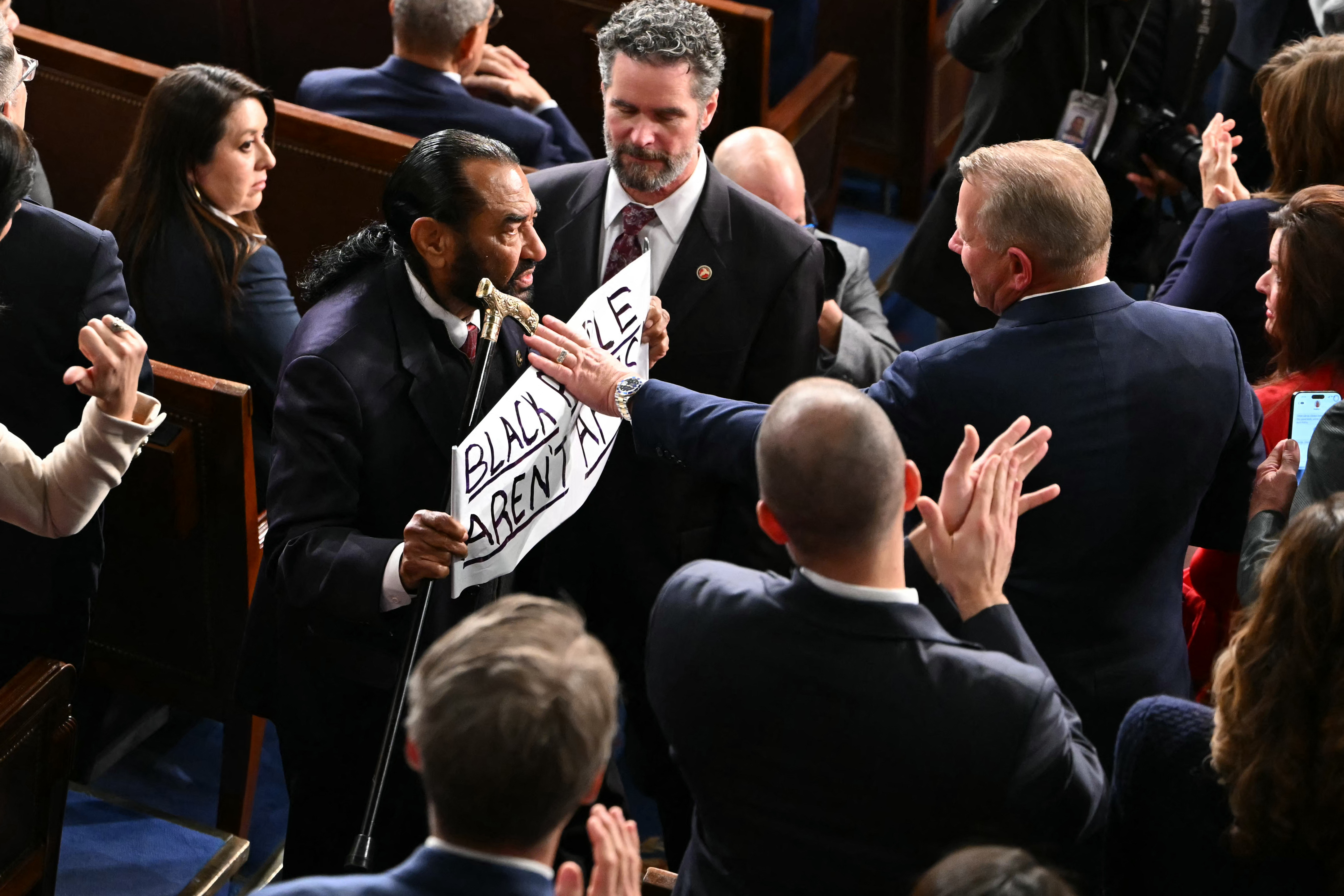 Rep. Al Green, Democrat from Texas, holds a sign reading “Black people aren’t apes” as he exits the House chamber during President Donald Trump’s State of the Union address at the U.S. Capitol in Washington, DC, on February 24, 2026. | Source: Getty Images
