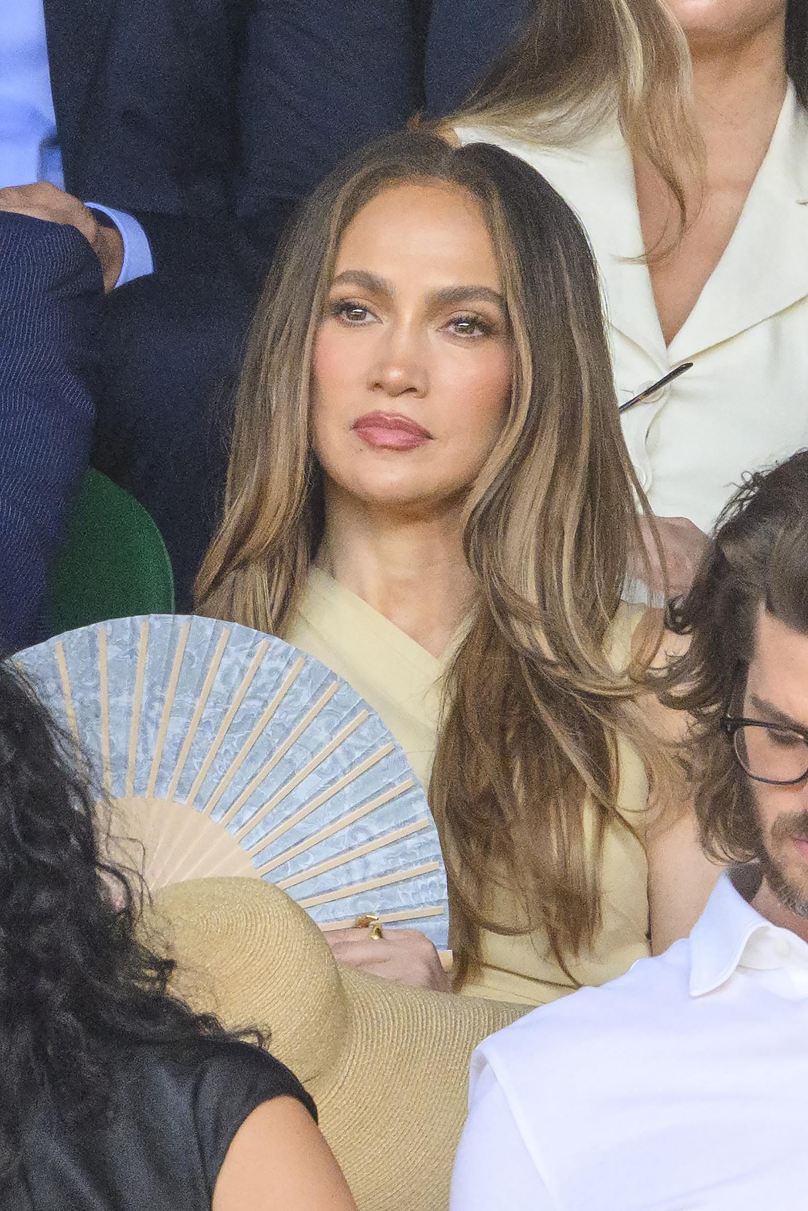 A decorative folding fan added another refined detail to the neutral look while offering relief from the summer heat. The accessory complemented her ensemble without generating the same heated response as the hat. | Source: Getty Images