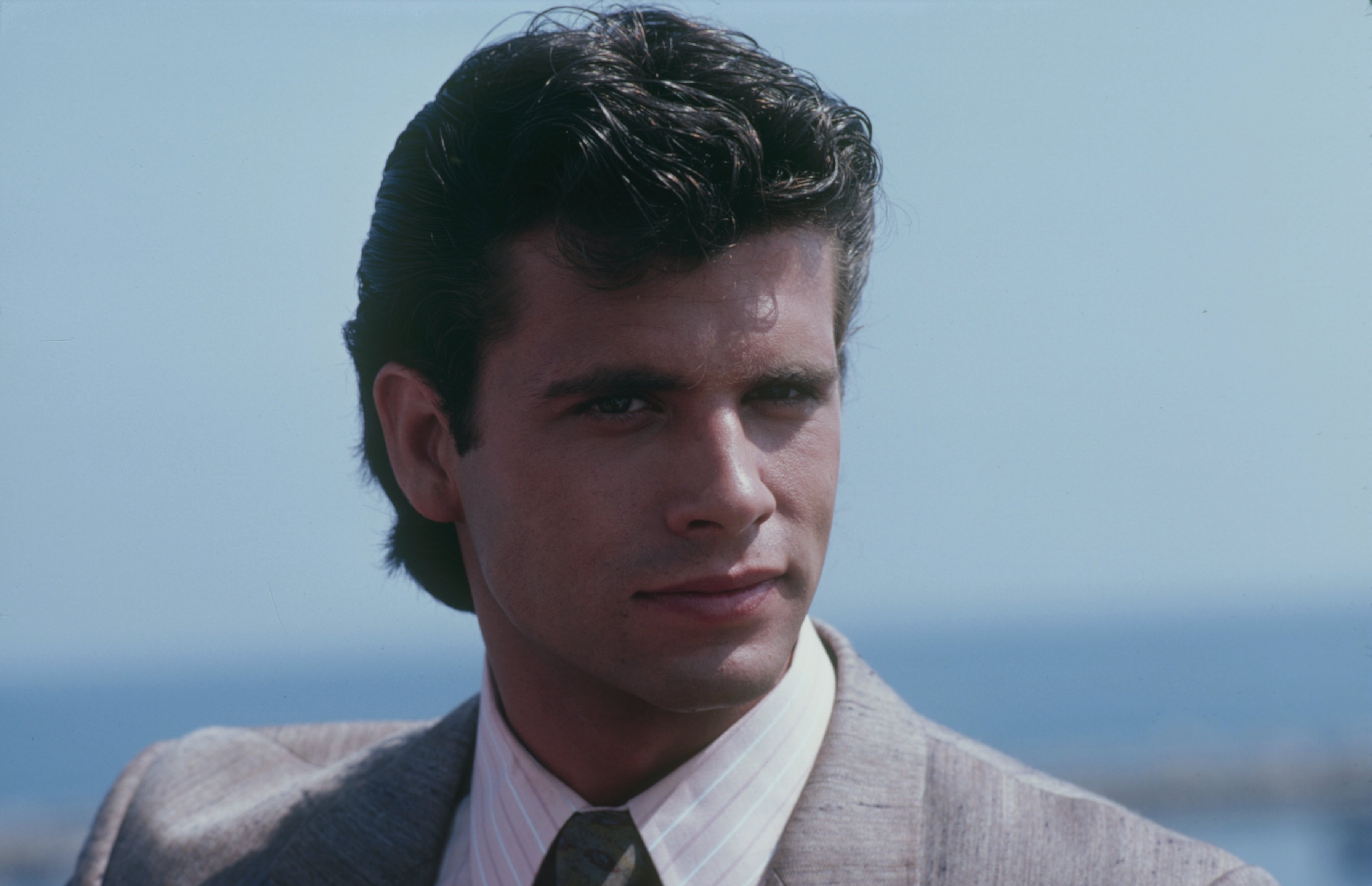 By 1983, Lorenzo Lamas had embraced a polished leading-man look while filming "The Love Boat." Dressed in a light-colored suit and tie, the actor appeared with carefully styled dark hair and the features that had helped establish his heartthrob status. The close-up came as his television career was gaining momentum, placing him firmly within the decade that would become closely associated with his early fame.