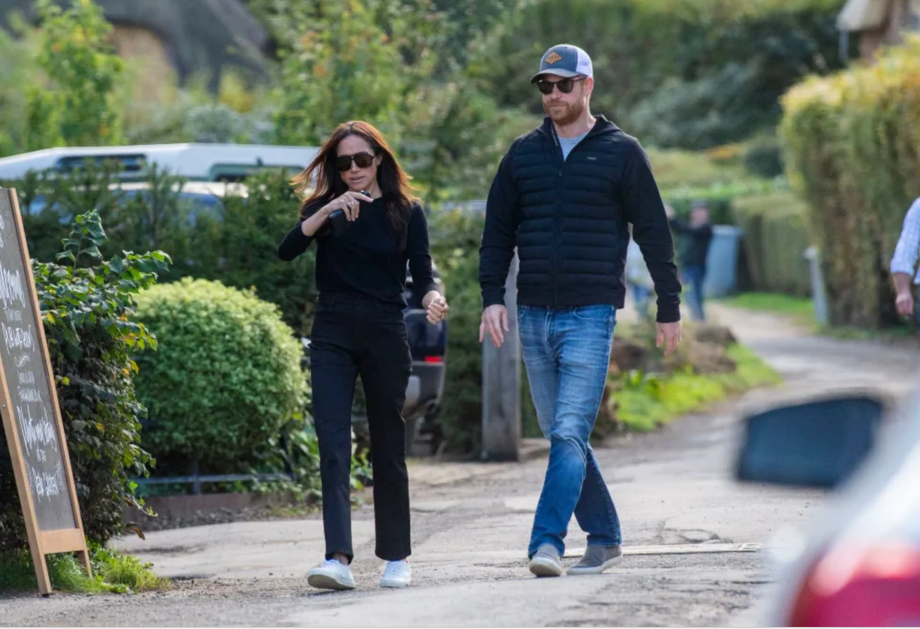 Prince Harry and Meghan Markle walk hand in hand along a country path in the Cotswolds on October 1, 2026, with both dressed casually for their pub outing. Harry wears a baseball cap and sunglasses, while Meghan gestures as they make their way toward the historic pub. | Source: Facebook/Prince Harry, Duke of Sussex