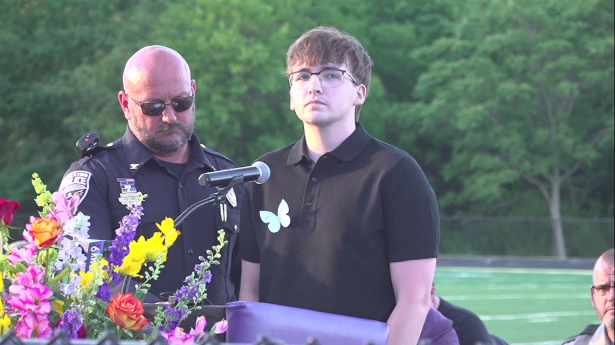 The Police Chief stands beside Jonathan McFarland who speaks during a community vigil for his family members killed in the Muscatine, Iowa, shooting spree. The sole surviving sibling addressed mourners as the community gathered to honor the victims. | Source: Facebook/Trending News Tracker
