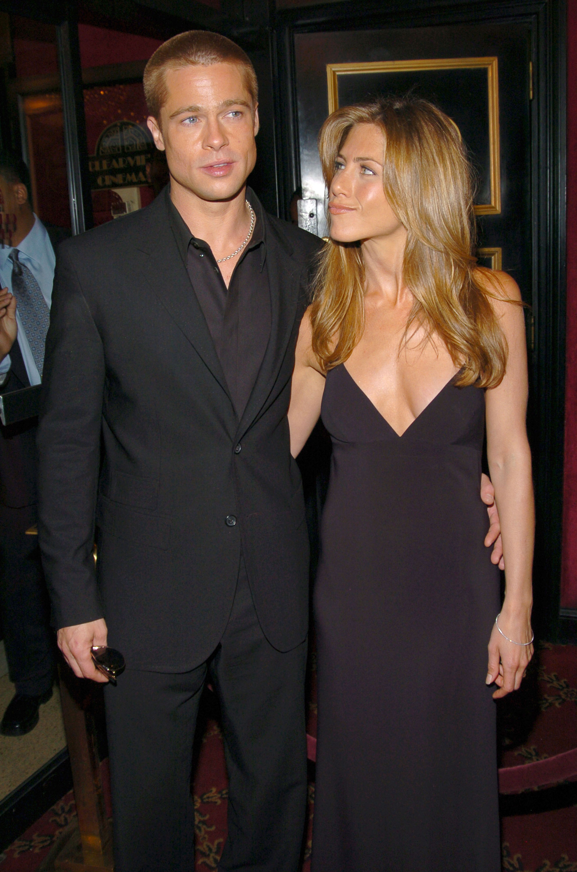 Brad Pitt and Jennifer Aniston arrive together at the "Troy" New York premiere, with Aniston looking toward Pitt as the couple poses closely for photographers outside the theater.