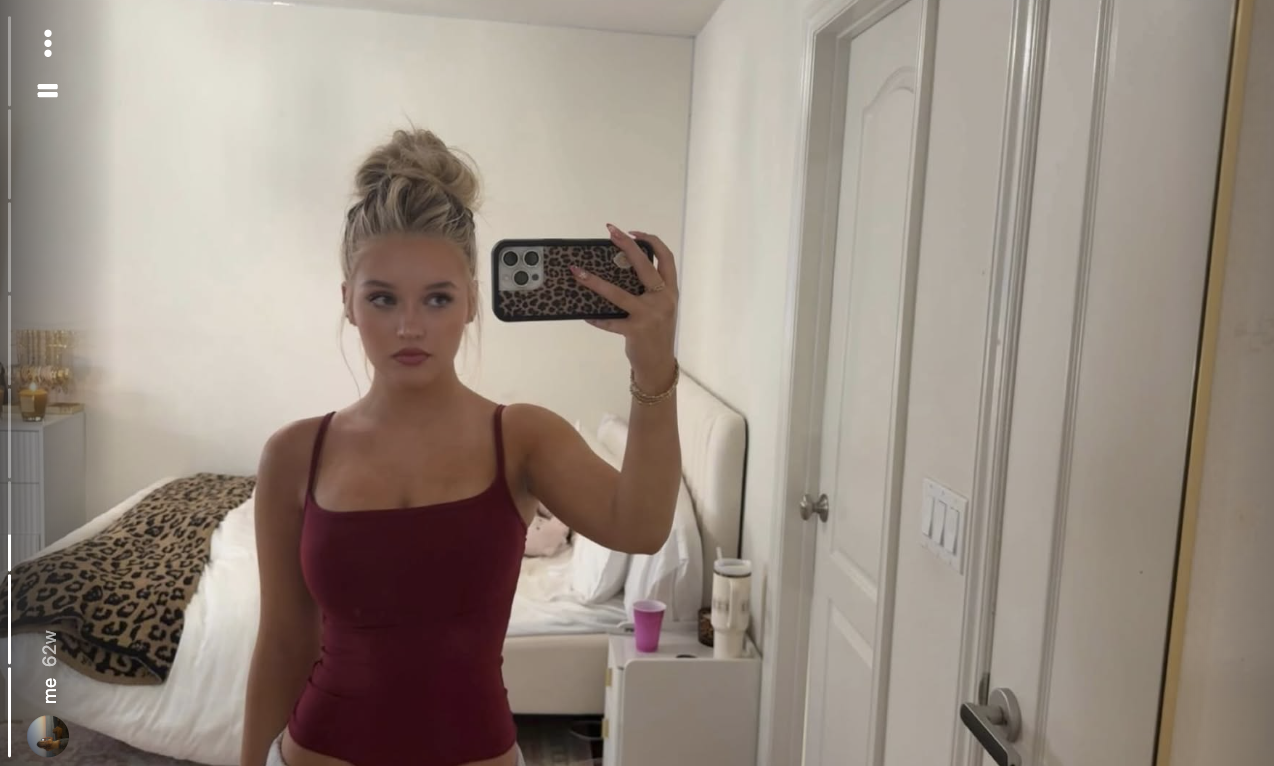 Finley Lockwood captures a casual mirror selfie in her bedroom, wearing a deep maroon square-neck camisole top with her blonde hair swept up into a high, tousled bun. | Source: Instagram/finleyl.ockwood