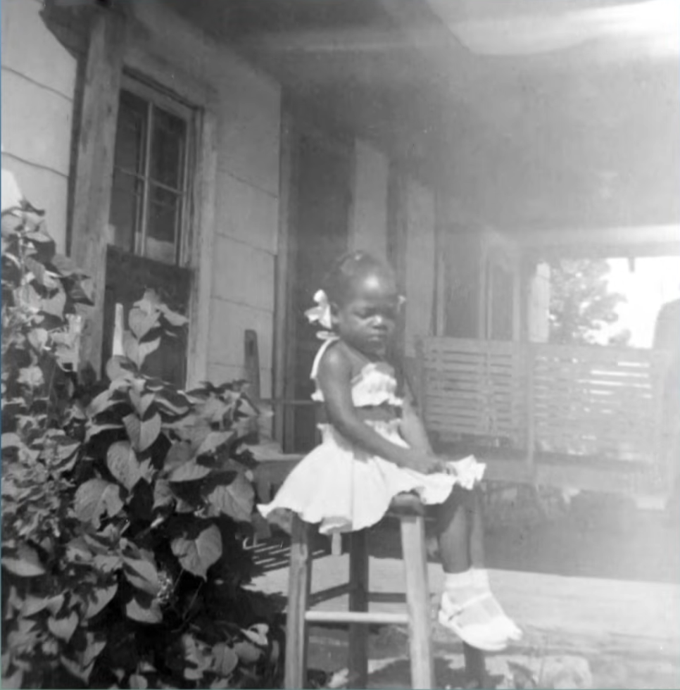 The legendary TV host as a young girl in front of her childhood home, from a video dated April 30, 2021 | Source: YouTube/DoctorOz