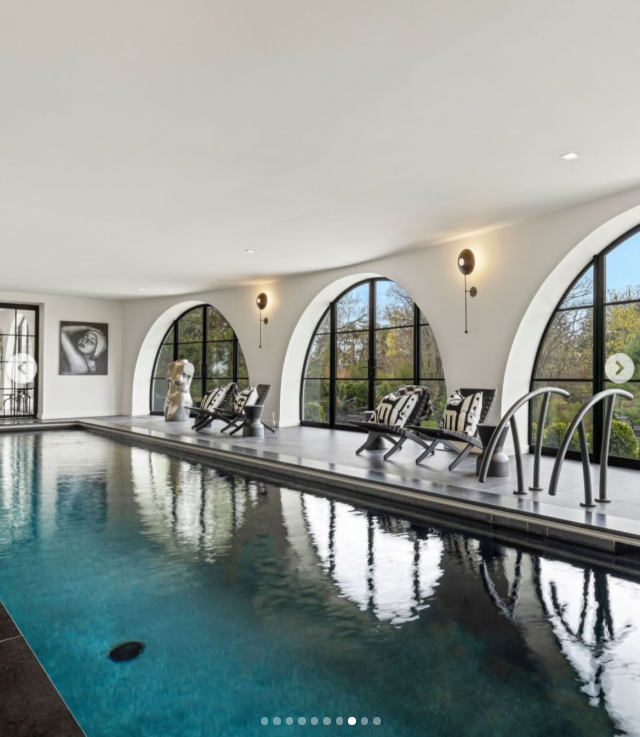 The indoor pool sits beside a row of oversized arched windows that bring the surrounding greenery into view. Lounge chairs line the water, turning one of Longmeadow's lower-level amenities into a private year-round retreat. | Source: Instagram/rogerperrygroup