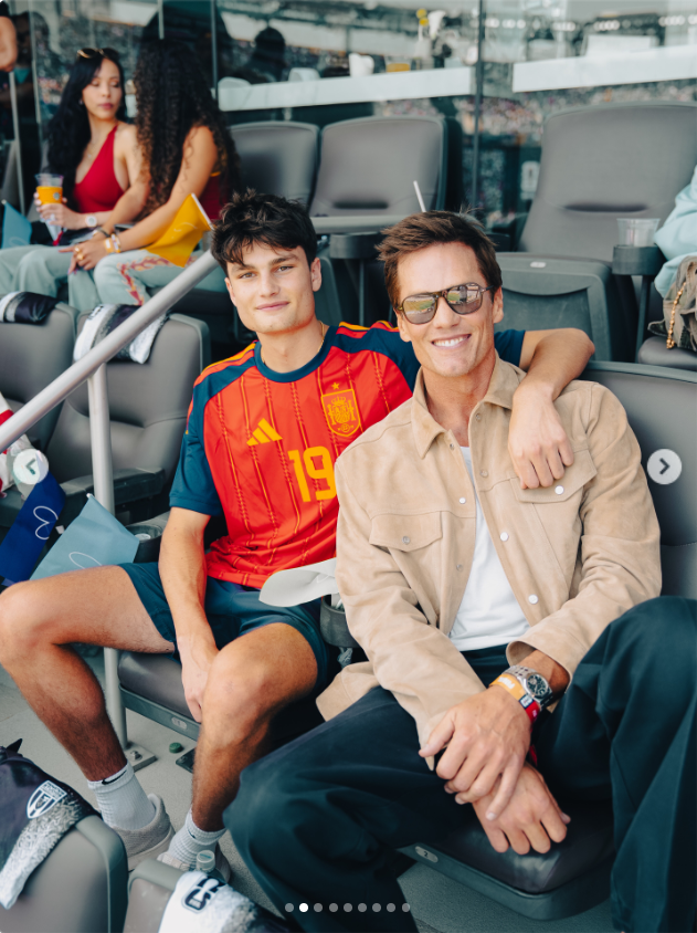 Tom Brady shares a relaxed moment with his son Jack at a football event, with the two smiling together in the stands. The photo offers another glimpse of how the former NFL star makes time for his children and enjoys sporting occasions alongside them. | Source: Instagram/tombrady