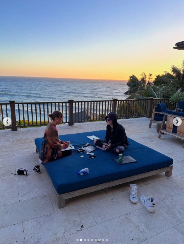 Wood and Gerber sit together on an oceanfront patio in one of the images she shared. The relaxed moment was among the personal snapshots Wood selected for her remembrance. | Source: Instagram/lexiwood