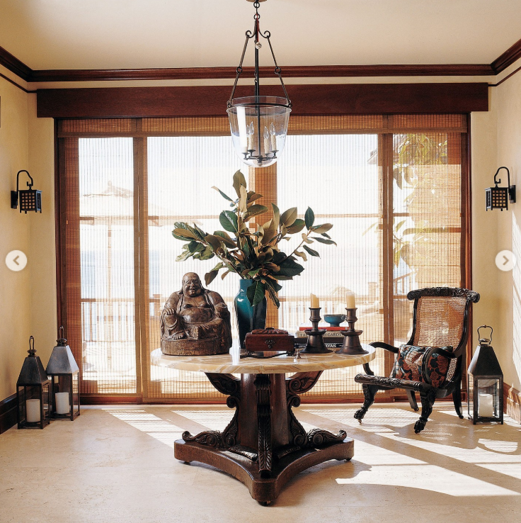 A round table anchors the home's sunlit entry, framed by dark wood and views toward the water. Cindy said the table came from her New York apartment and was placed there after the house was evaluated for feng shui. | Source: Instagram/elledecor