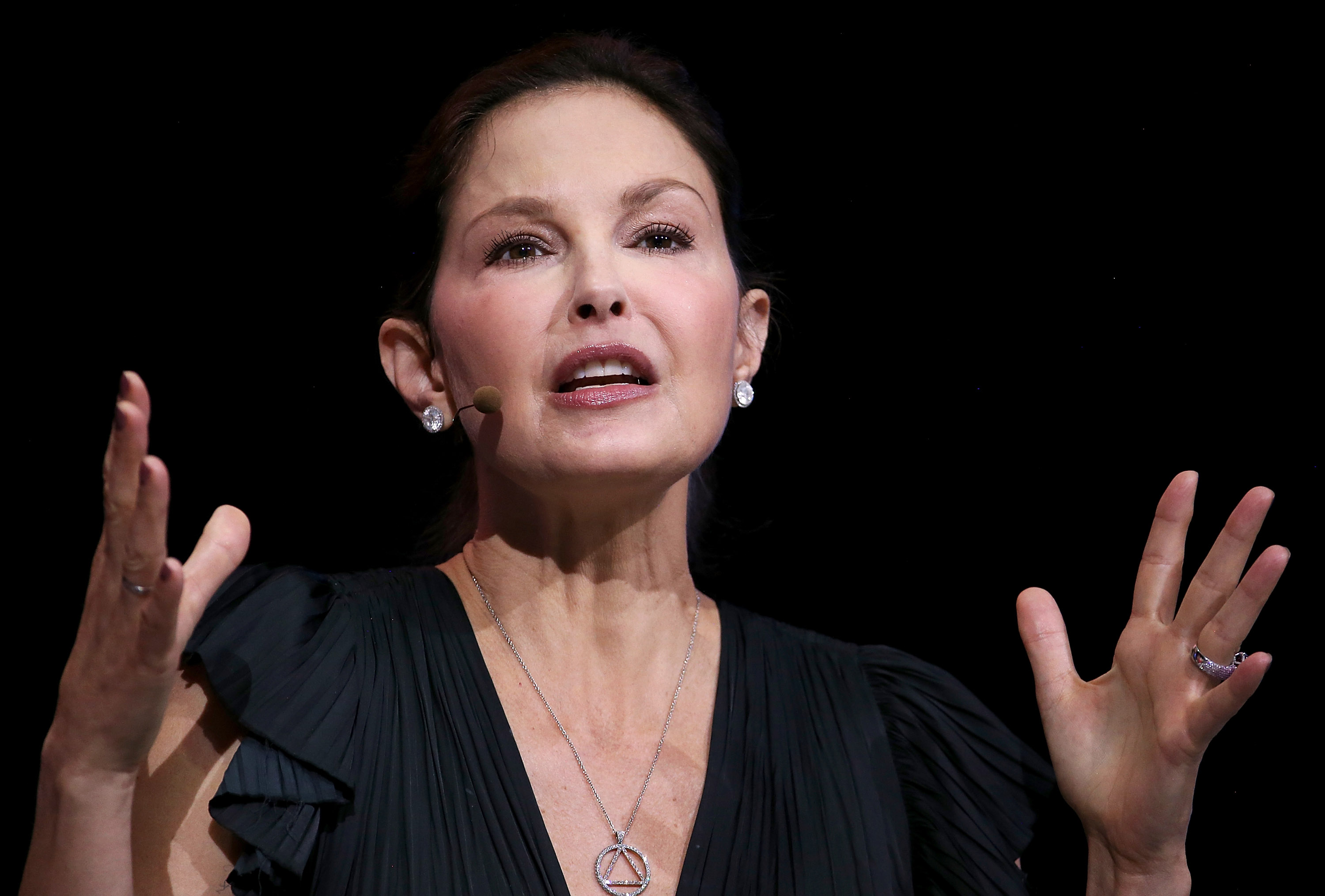 With her hair pulled back and both hands raised, Judd addressed the Professional BusinessWomen of California conference in April 2018. The stage lighting and close camera angle reveal details of her facial expression as she speaks.